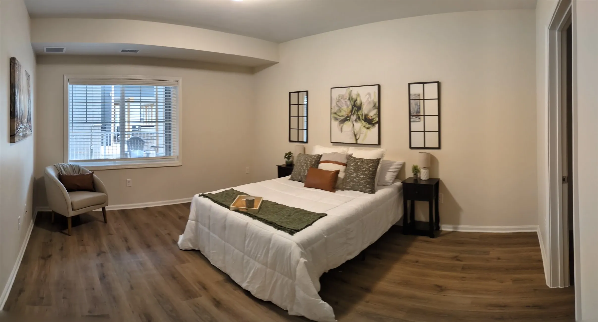 Spacious room featuring wood-finish flooring, a large window with blinds, light neutral wall paint, and white trim