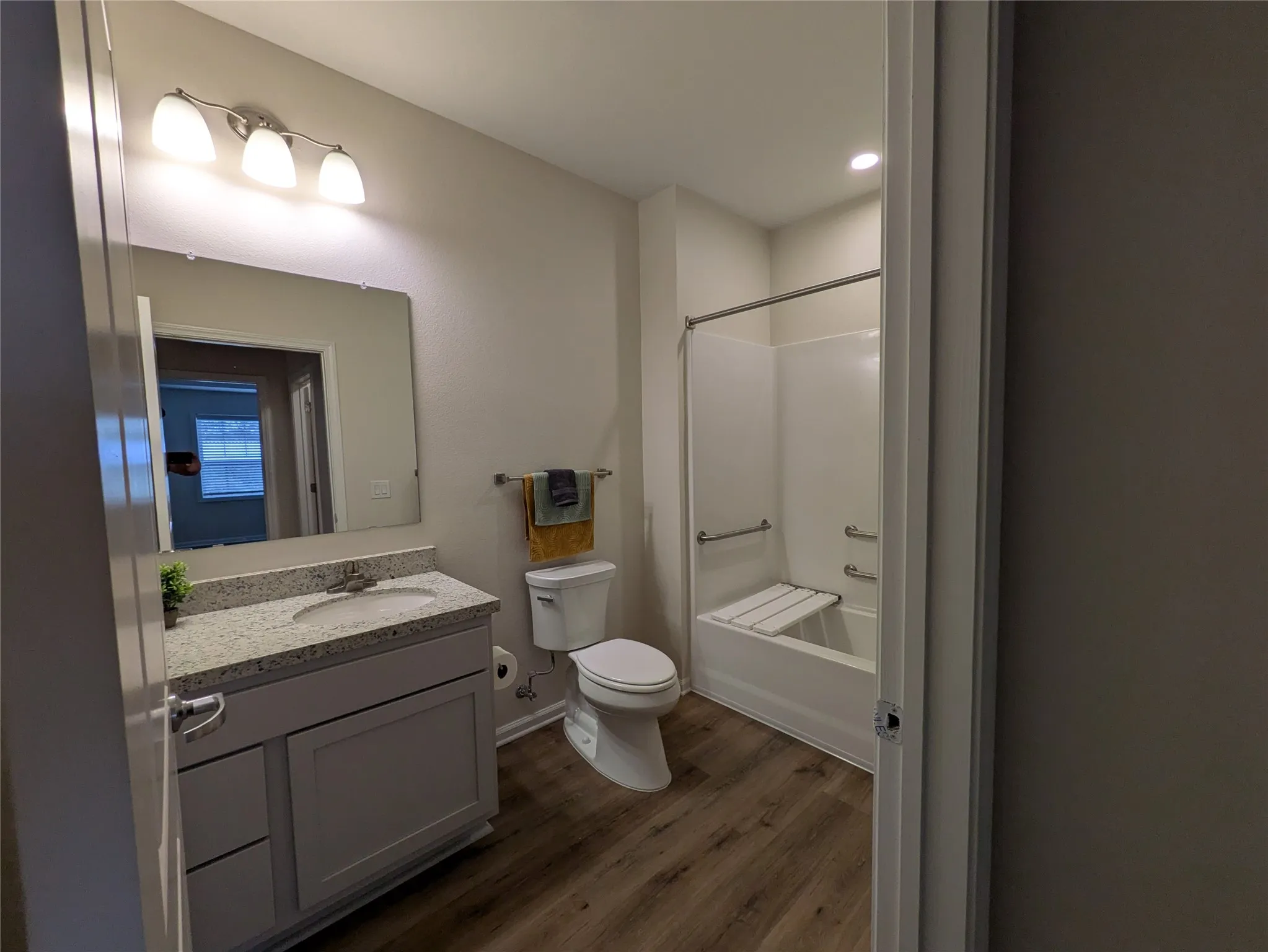 Bathroom featuring a single vanity with a stone-finish countertop, undermount sink, and light gray cabinetry