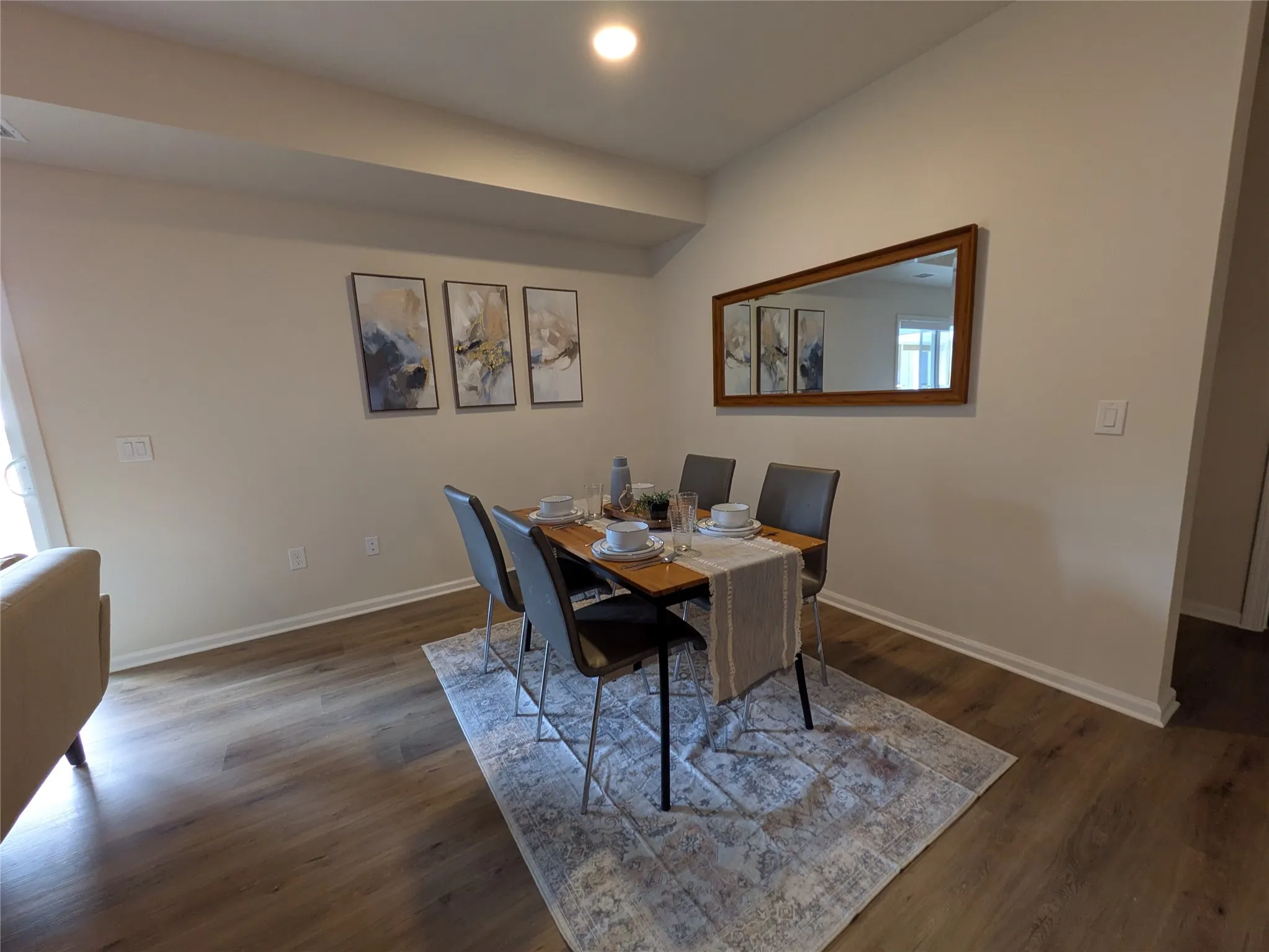 Dining area featuring wood-finish flooring, light-colored walls, white baseboards, and a vaulted ceiling