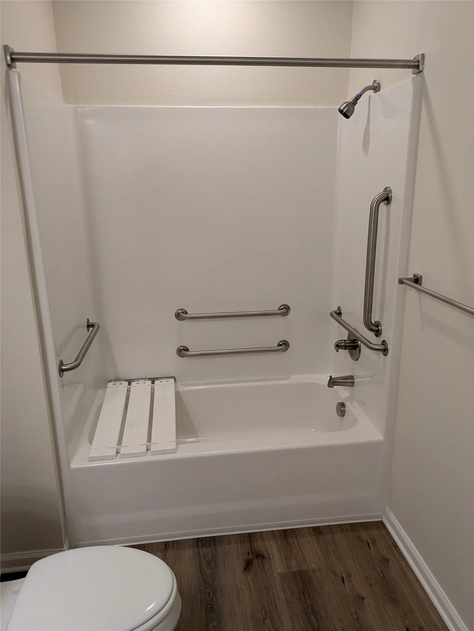 White bathtub and shower combination unit featuring a brushed nickel showerhead and faucet