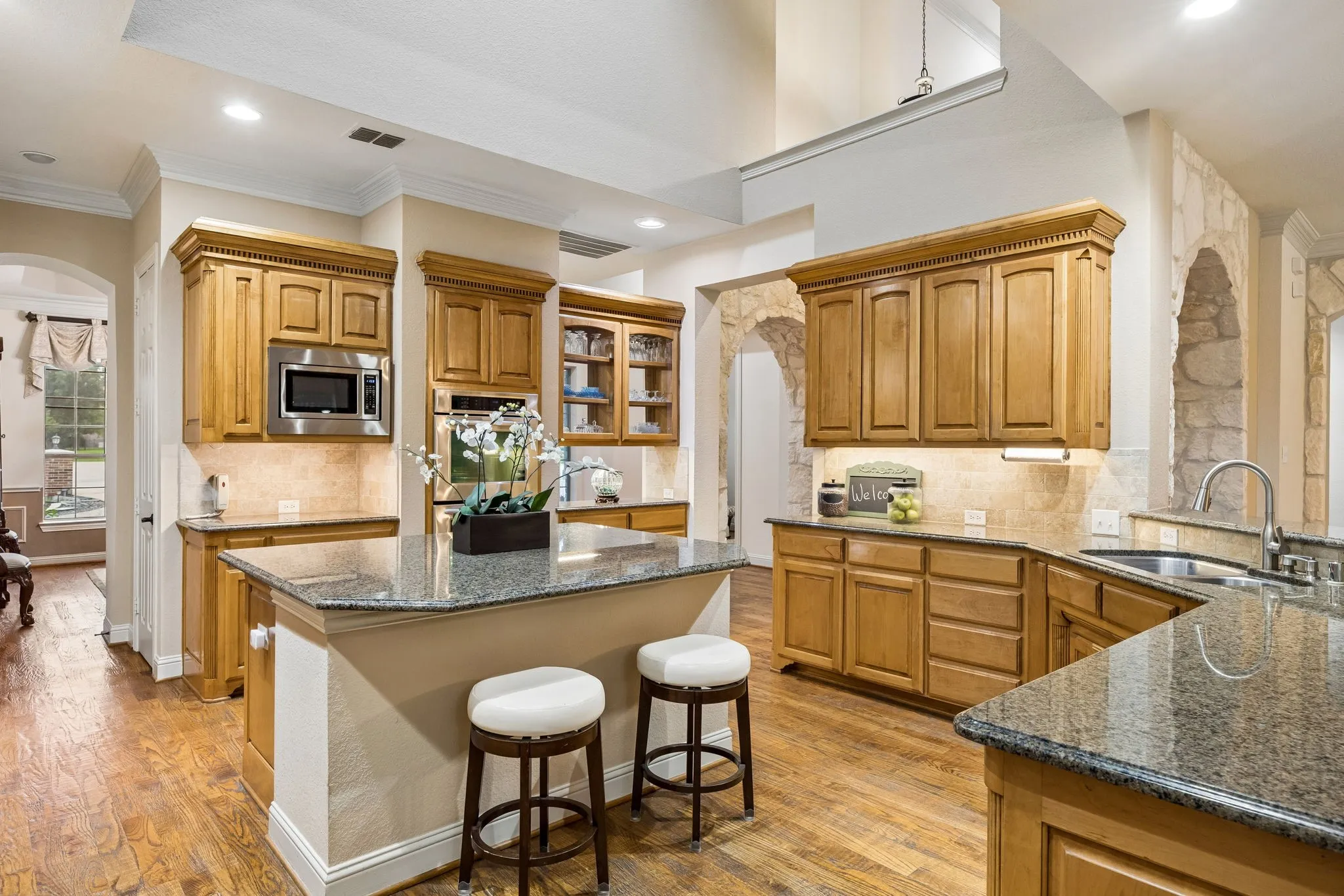 The large island is all workspace with bar seating for convenience. High ceiling keeps a space open and airy.