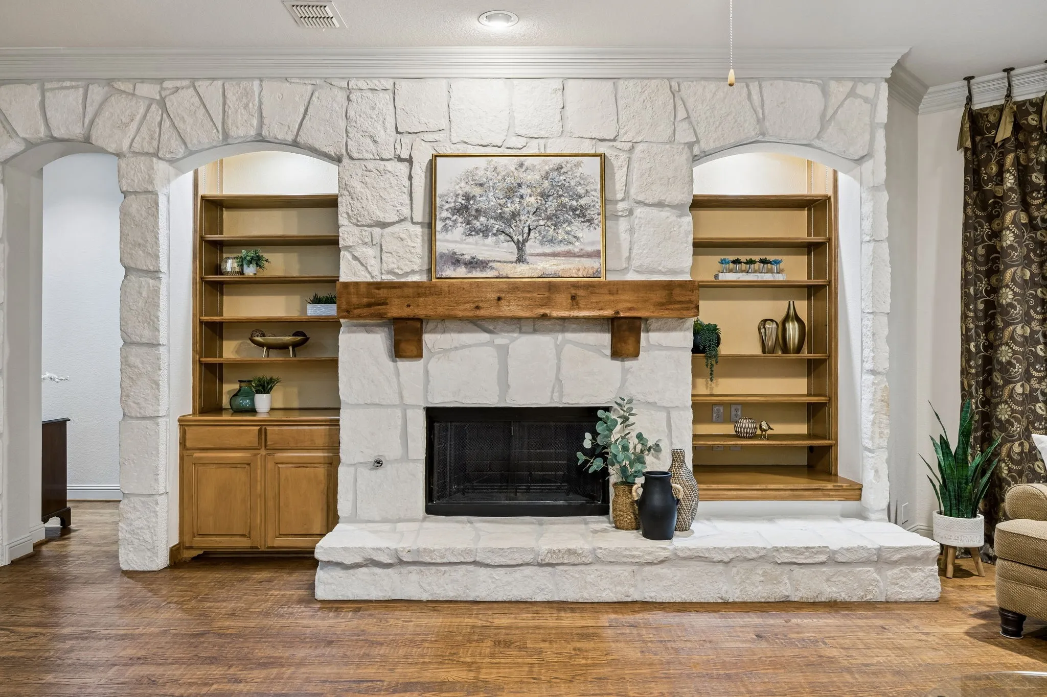 This beautiful gas, stone fireplace is wood burning
and boasts a lovely cedar mantel. The stonework
extends to cover the entire wall. Built-in
bookshelves add to the charm. The arched opening
seen to the left leads to the sleeping quarters.