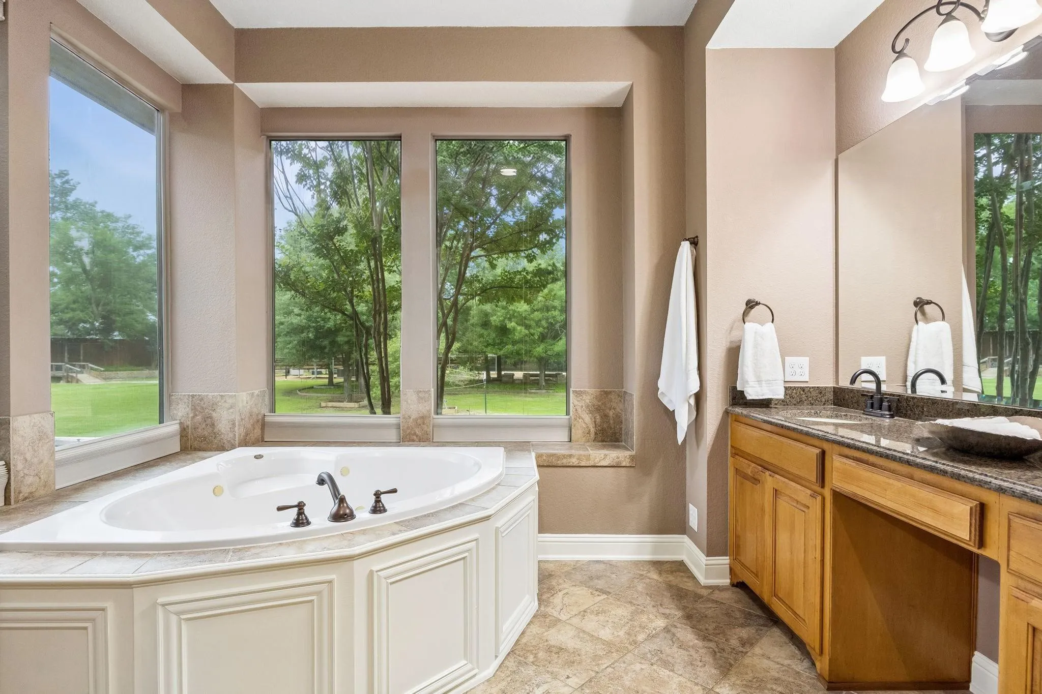 This jetted tub is surrounded by windows that
overlook the gorgeous backyard. No privacy
worries with motorized shades! Tile surround offers
space for lotions and potions.