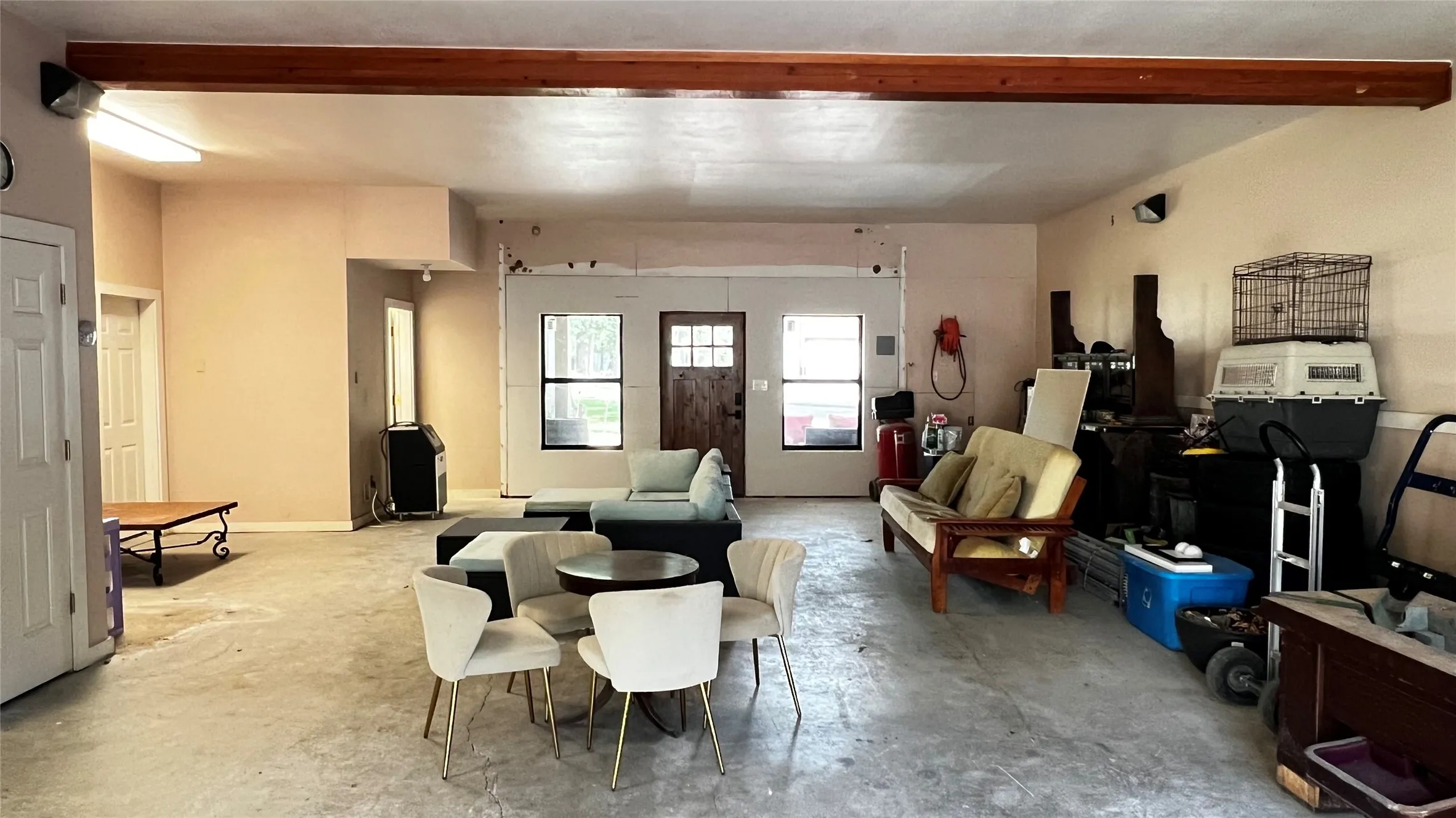 Finished garage space with front door flanked by windows accessing the Red Oak Rd covered patio and driveway.  The Primary Bedroom Suite and Laundry room access doors on the left side of th photo