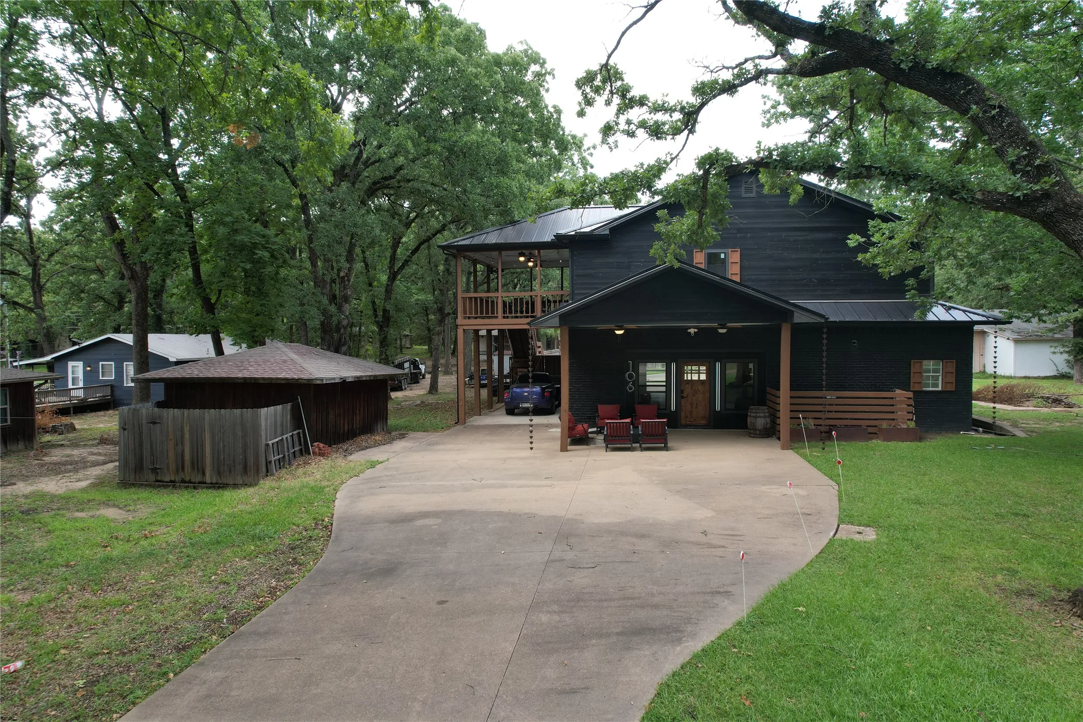 Red Oak Dr house front with spacious covered downstairs Barndo garage living area entrance, plus covered side patio or carport with access to fenced barkyard and stairs to upper covered deck.