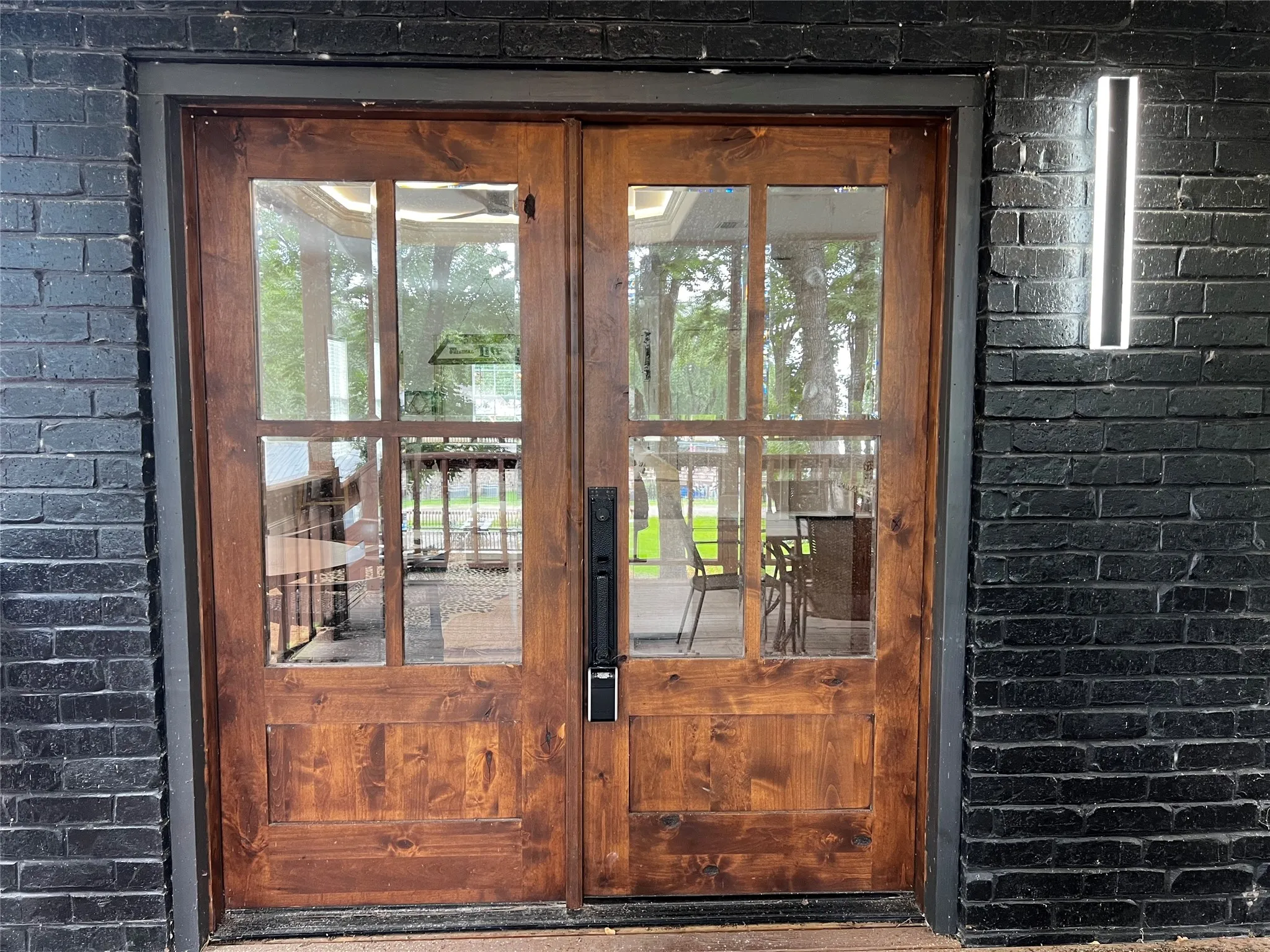 Upstairs Living space Solid wood double entry doors with multiple glass lites and dark hardware under a large covered deck with lake views