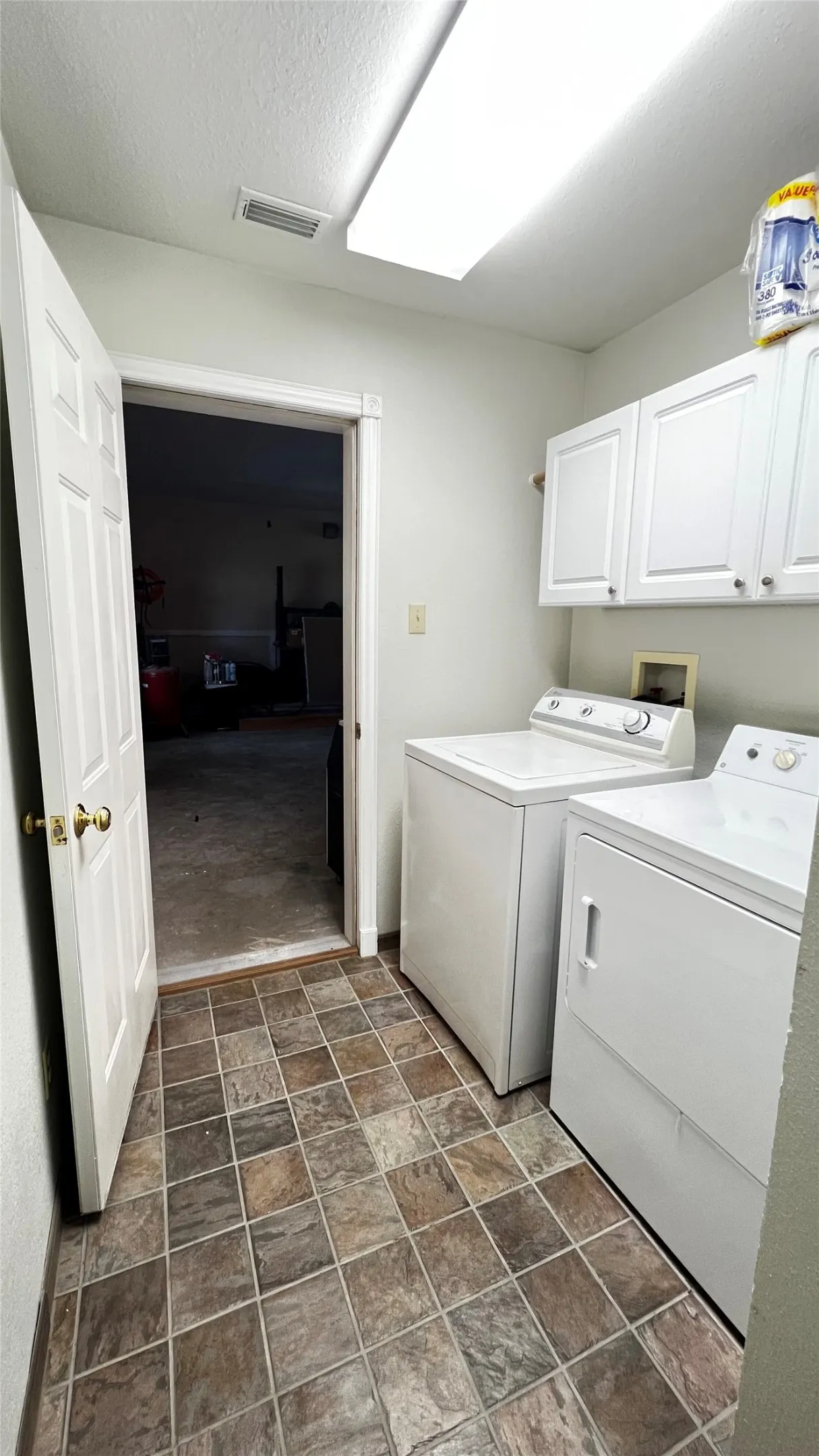 Dedicated laundry area on ground floor featuring patterned tile flooring and overhead white cabinetry