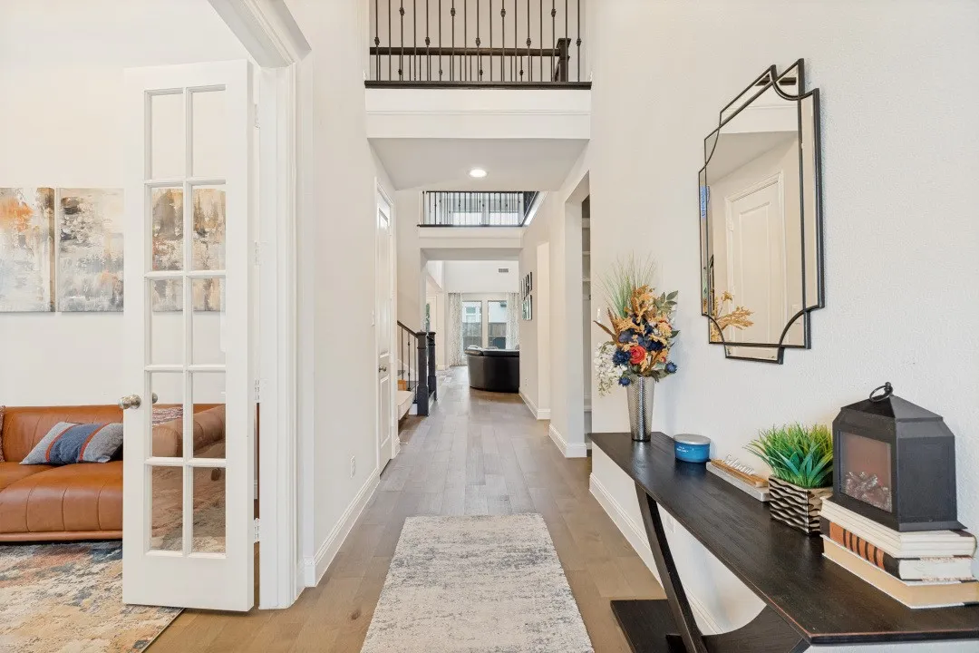 Two-story entry foyer featuring wood-finish flooring, white walls, and a wrought iron balcony railing