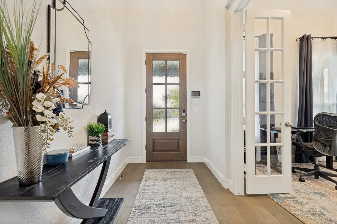 Entryway featuring a wood-panel door with privacy glass, wood-finish flooring, and crisp white walls