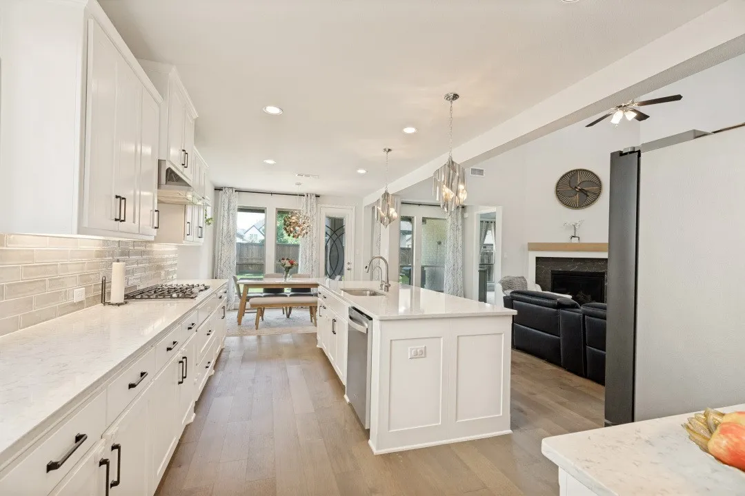 Modern kitchen featuring white cabinetry, light-toned countertops, a subway tile backsplash, stainless steel appliances, and wood-finish flooring