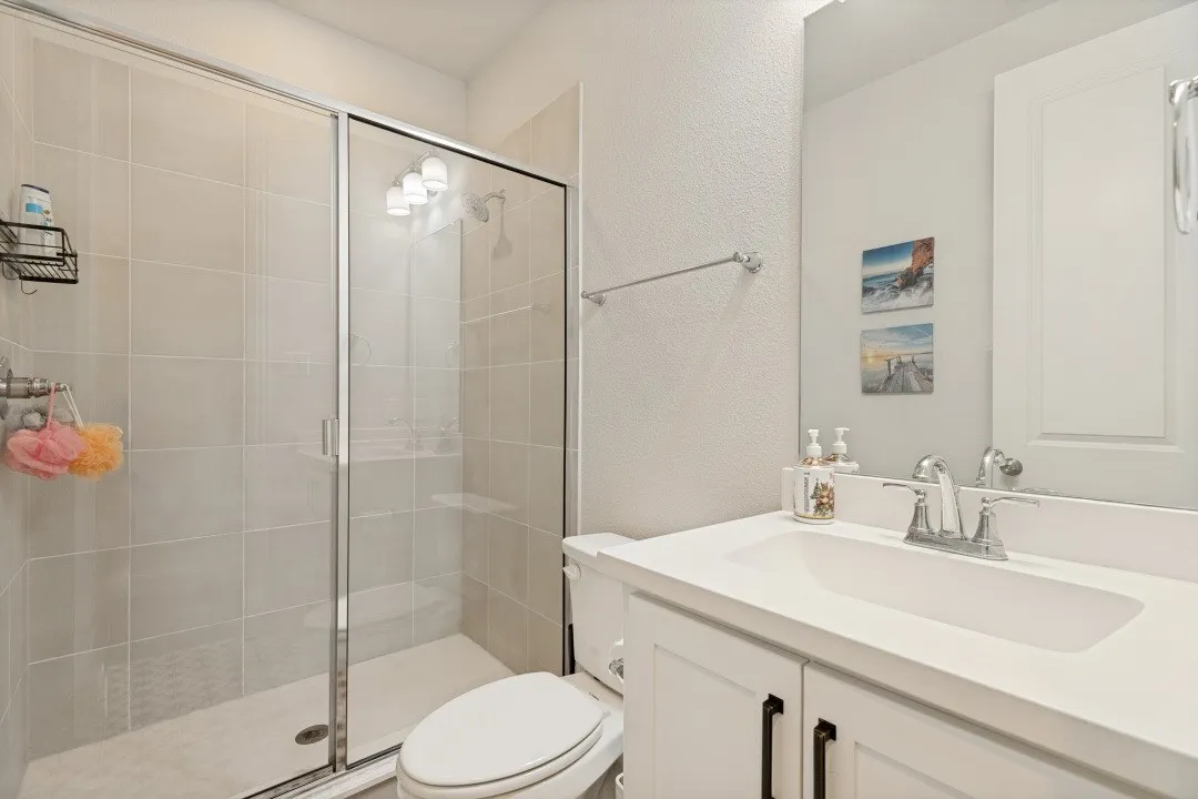 Bathroom featuring a glass-enclosed shower with light-toned wall tiling and a separate vanity with an integrated sink and base cabinetry