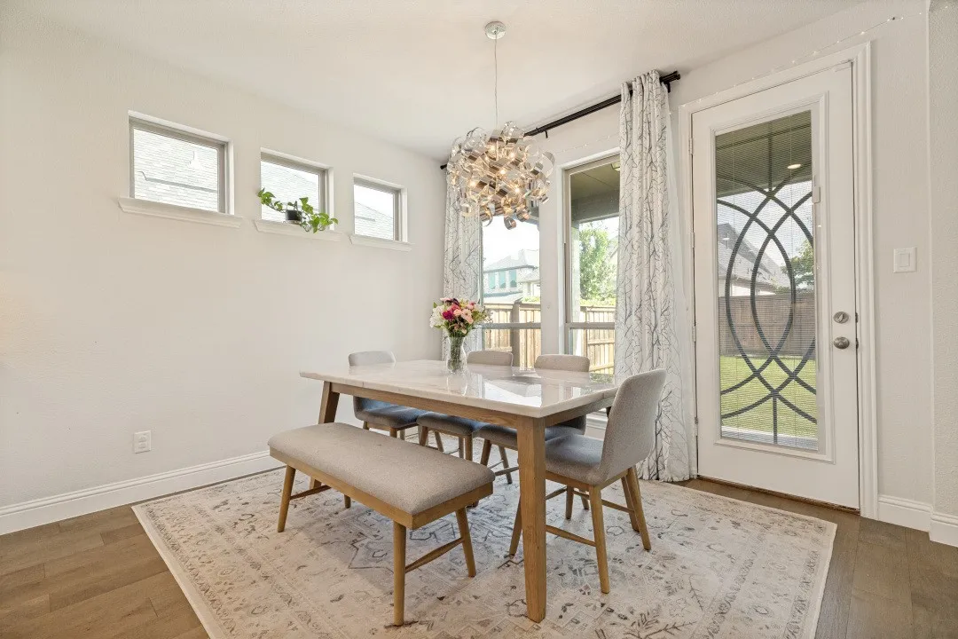 Dining area featuring a contemporary chandelier, wood-finish flooring, and a glass-paneled exterior door with decorative ironwork