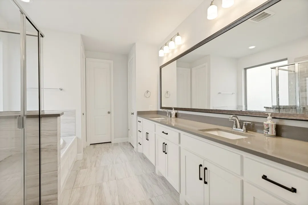 Contemporary bath featuring a dual vanity with undermount sinks, stone countertops, and white cabinetry