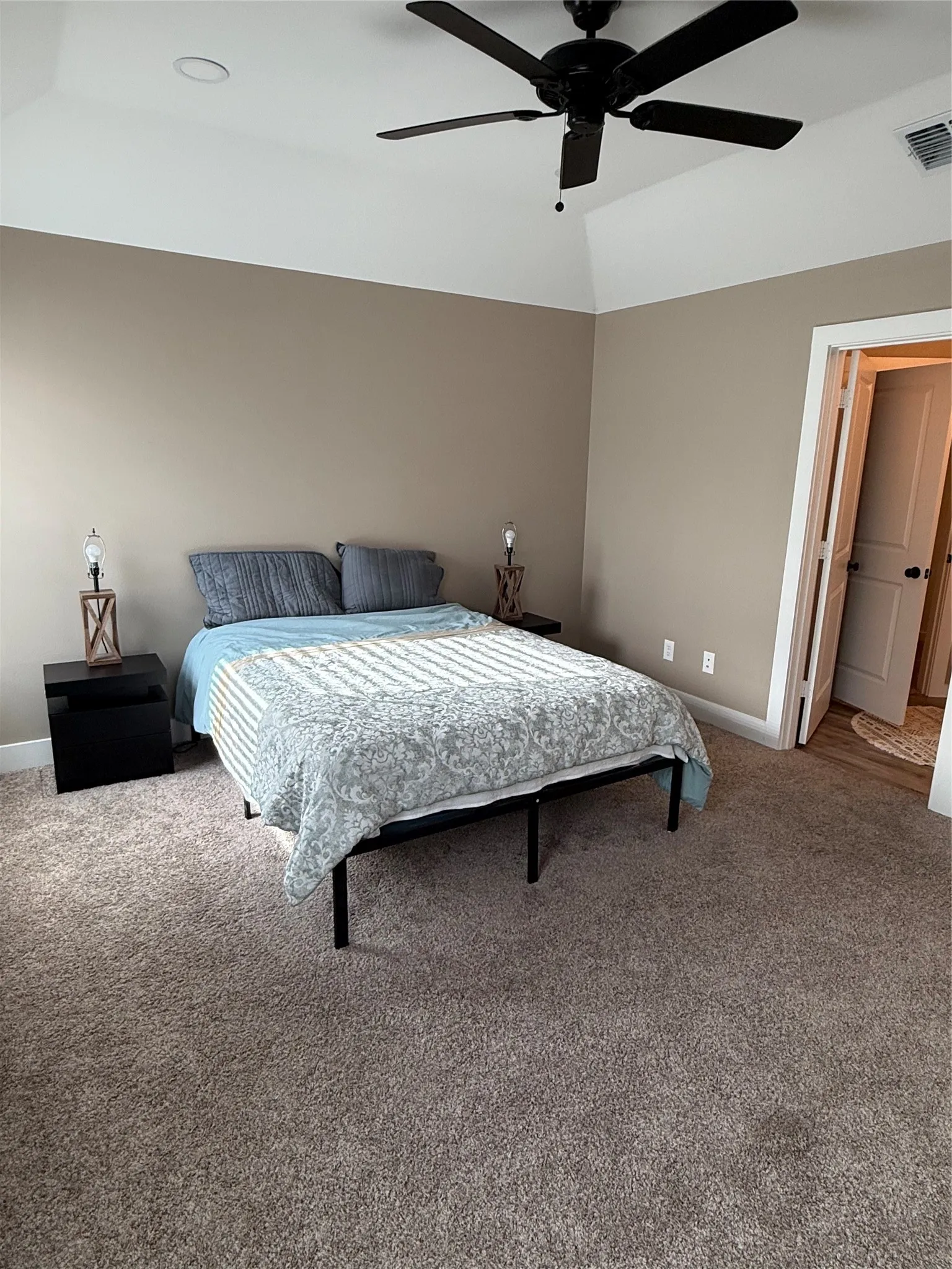 Carpeted bedroom with a vaulted ceiling, recessed lighting, and a dark-toned ceiling fan