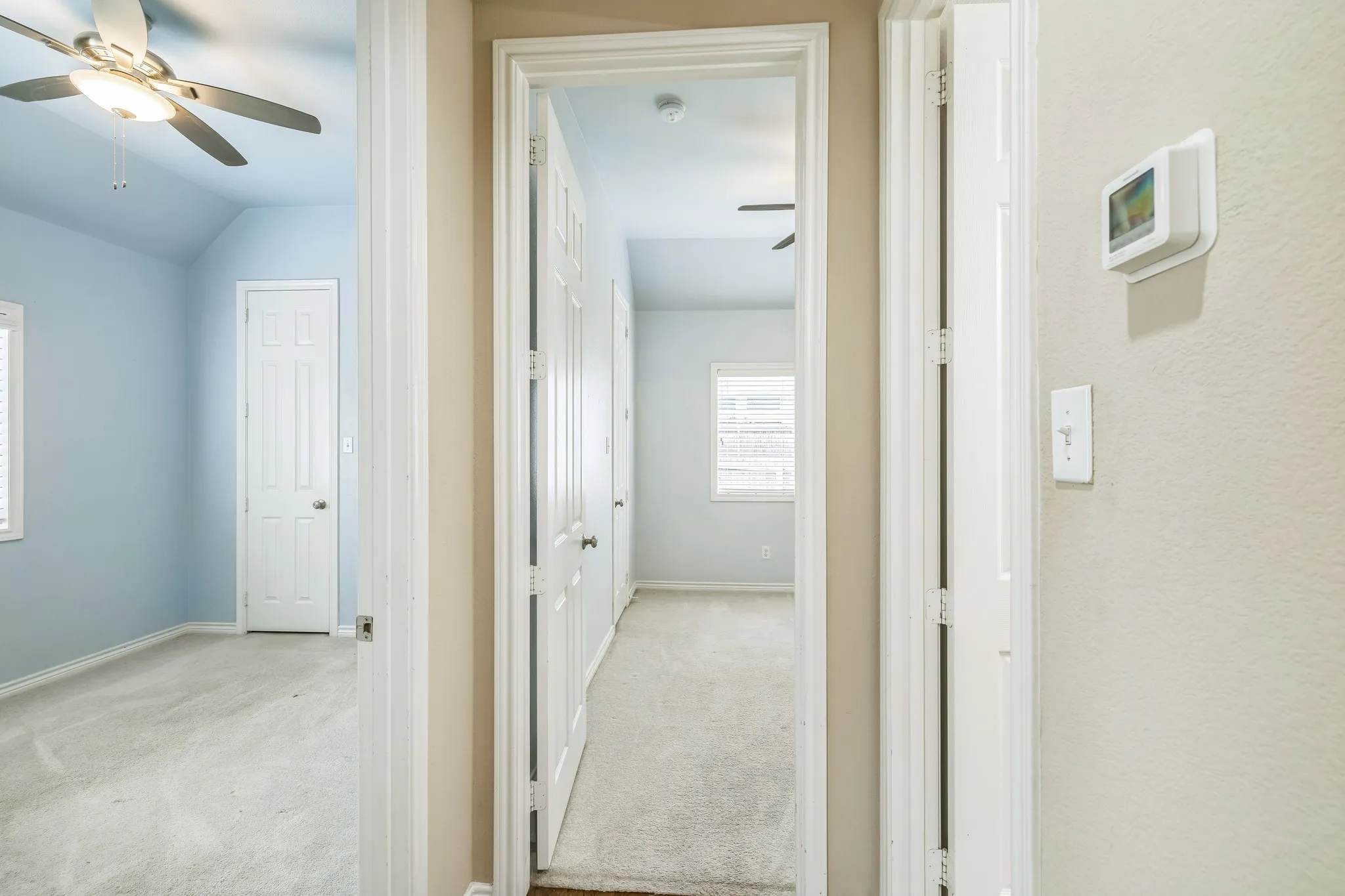 Hallway featuring carpeted flooring and a wall-mounted thermostat