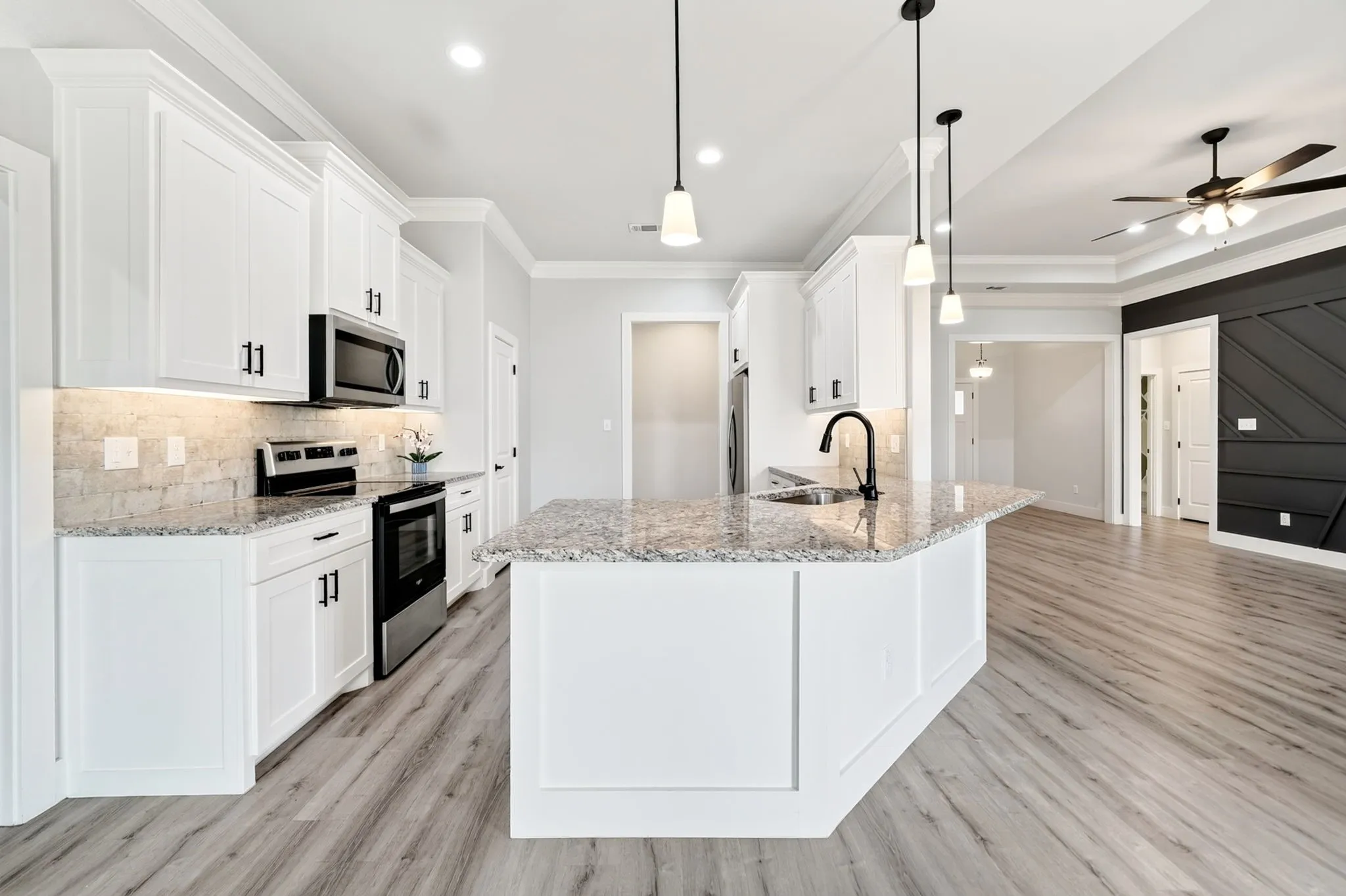 Contemporary kitchen featuring white cabinetry, light-toned granite countertops, and stainless steel appliances