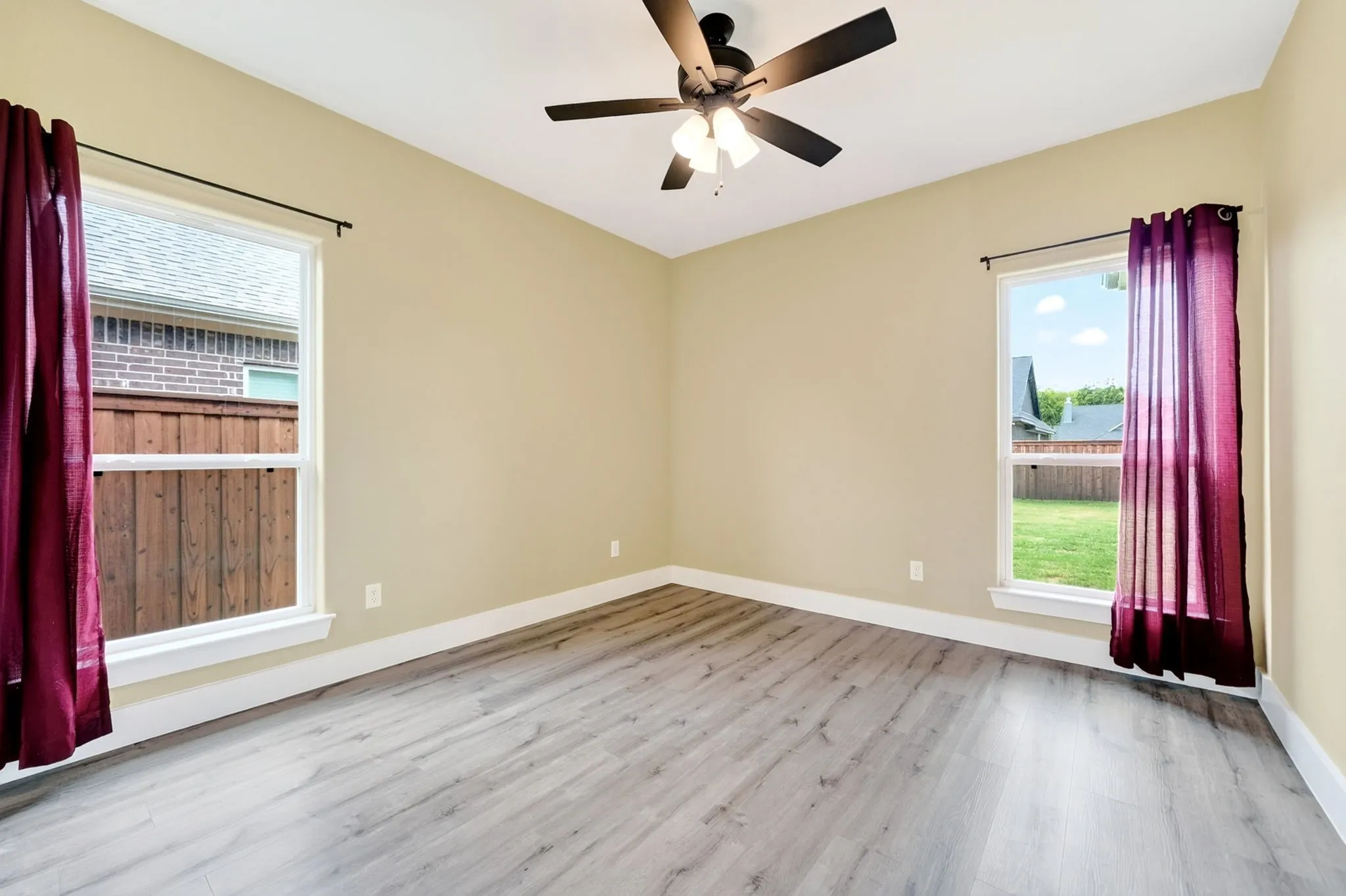 Spacious room with wood-finish flooring, light-toned walls, and white baseboards