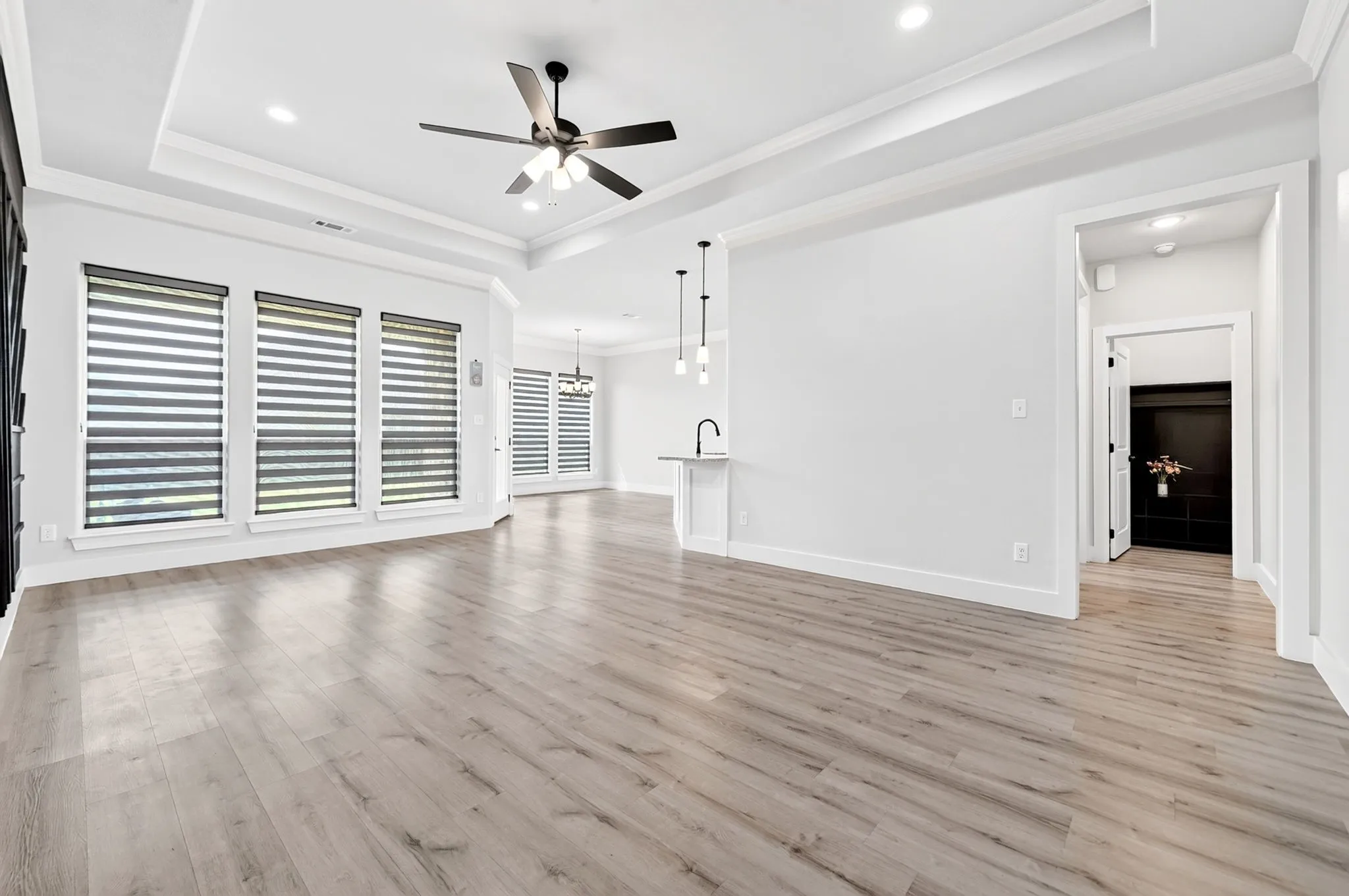 Spacious living area featuring wood-finish flooring, a tray ceiling, and recessed lighting