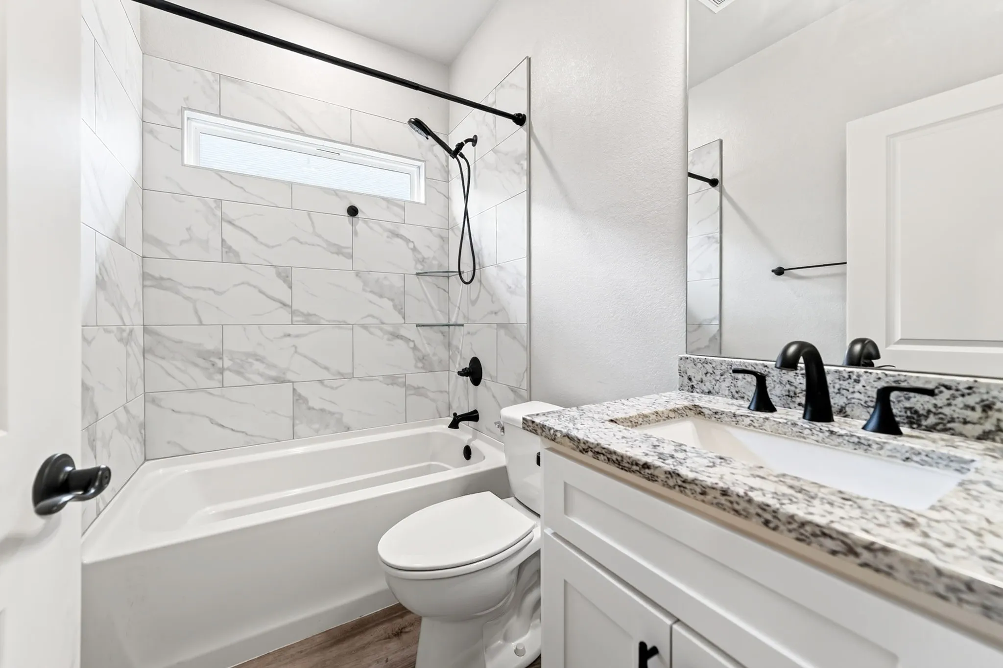 Bathroom featuring a white vanity with a speckled countertop, a rectangular undermount sink, and matte black fixtures