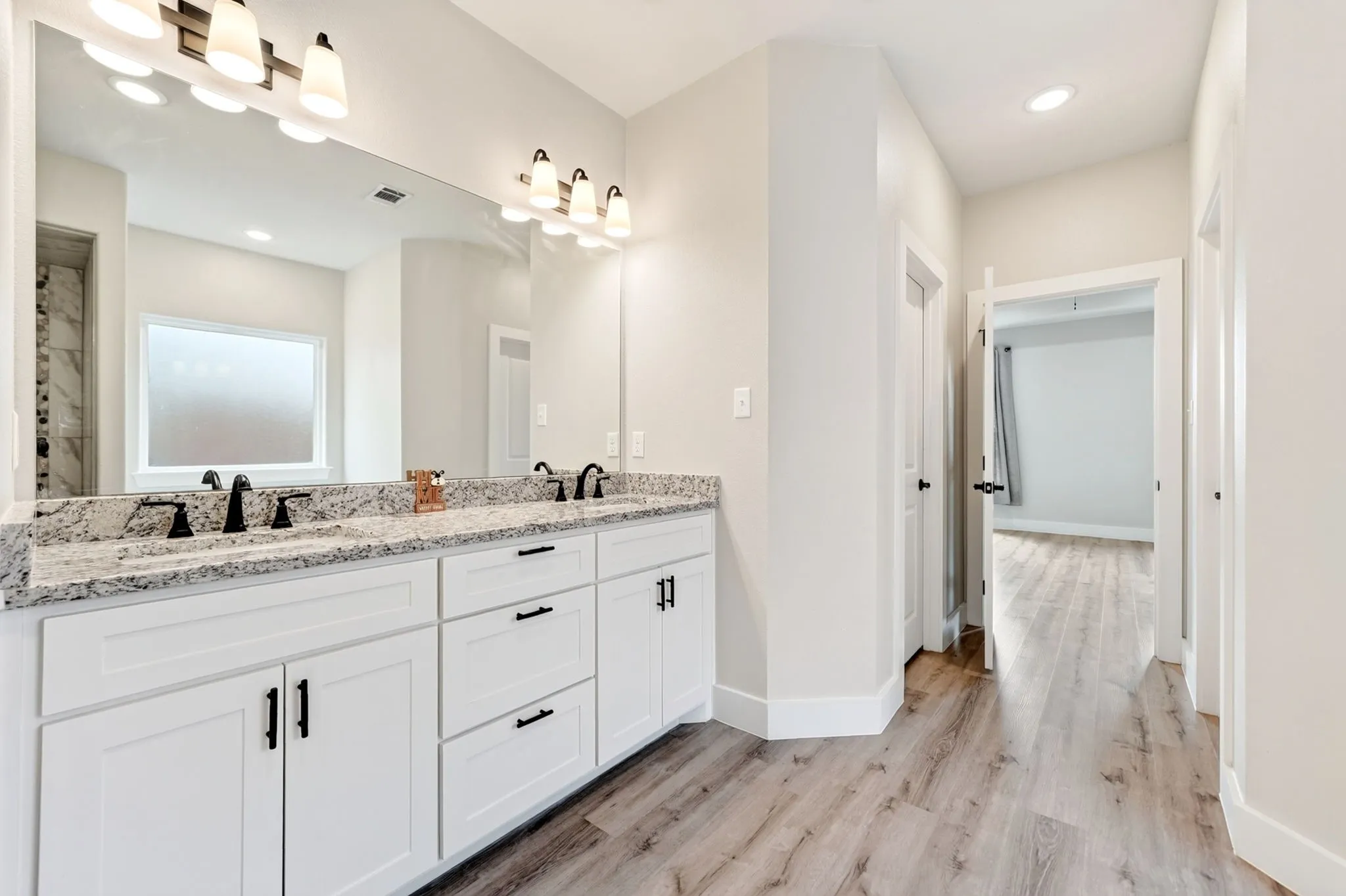 Double vanity with white cabinetry, matte black hardware, and speckled stone countertops