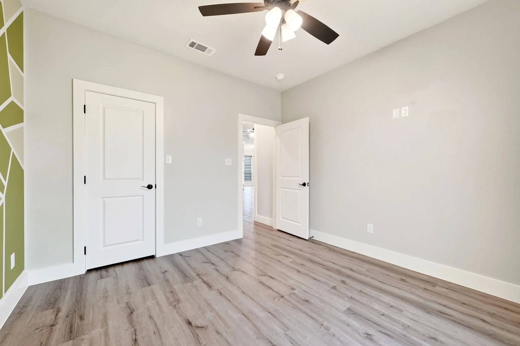 Room featuring wood-finish flooring, white baseboards, and light gray walls