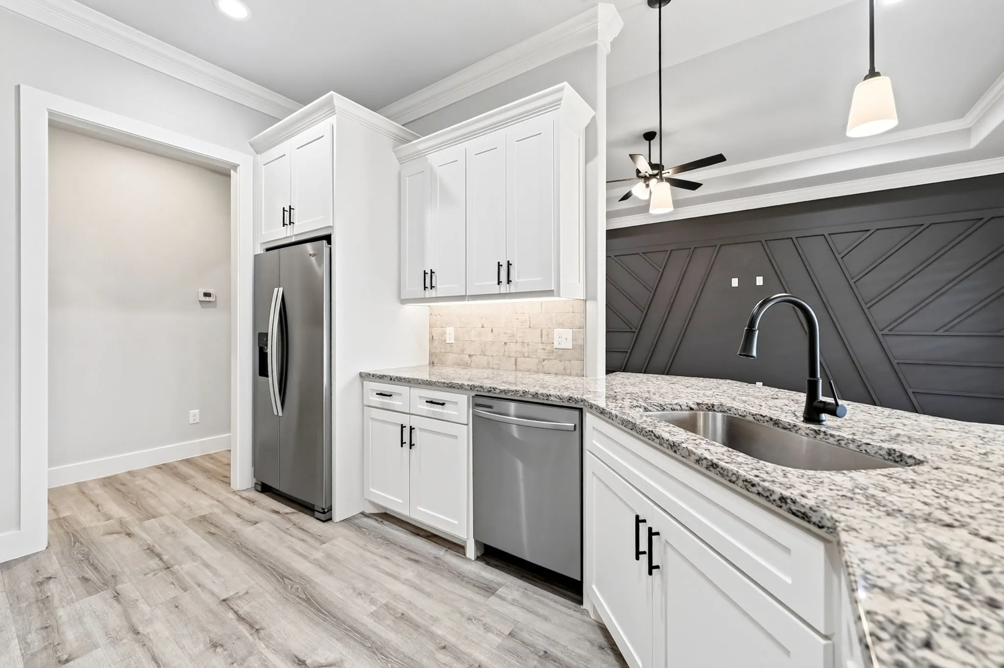 Kitchen featuring white cabinetry, stainless steel appliances, speckled stone countertops, and a subway tile backsplash