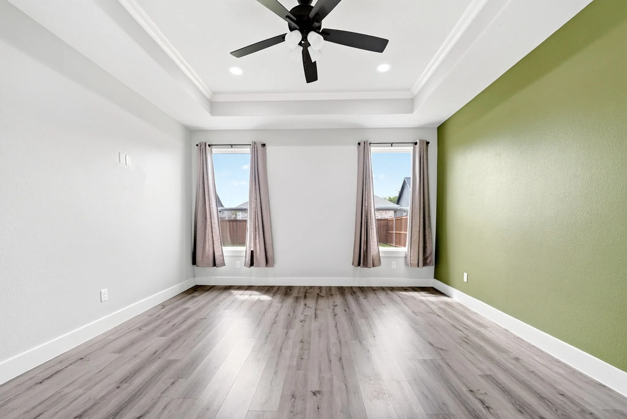 Spacious room featuring a tray ceiling with crown molding, a black ceiling fan, and recessed lighting