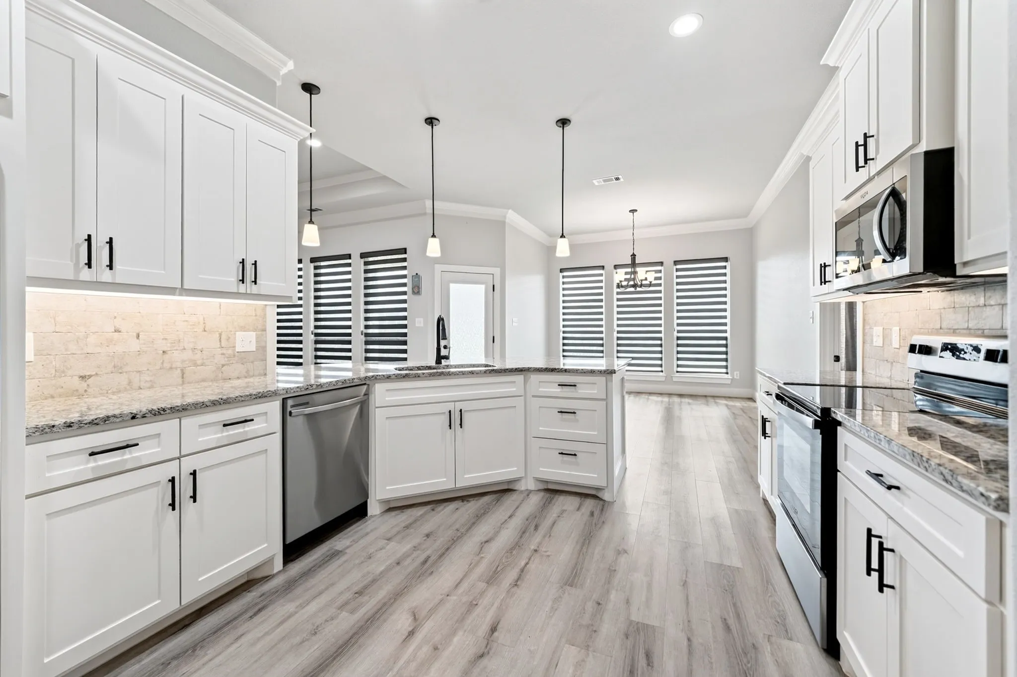 Modern kitchen featuring white cabinetry, light-toned wood-finish flooring, and stainless steel appliances