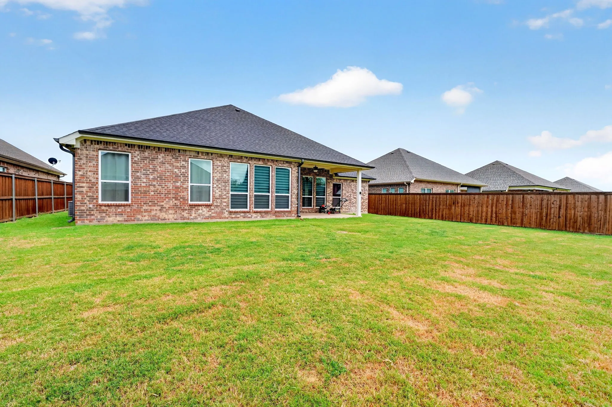 Expansive backyard with a brick exterior, covered patio, and privacy fencing