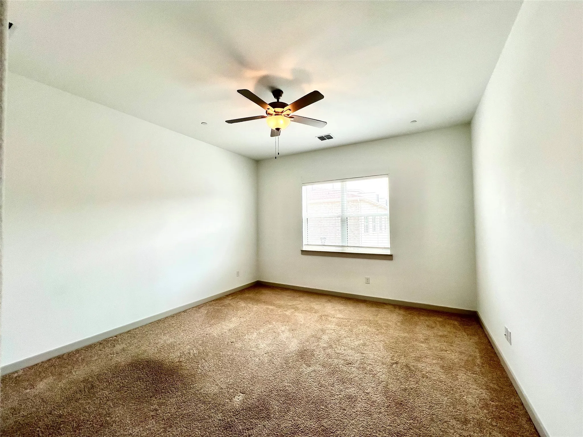 Carpeted empty room featuring ceiling fan