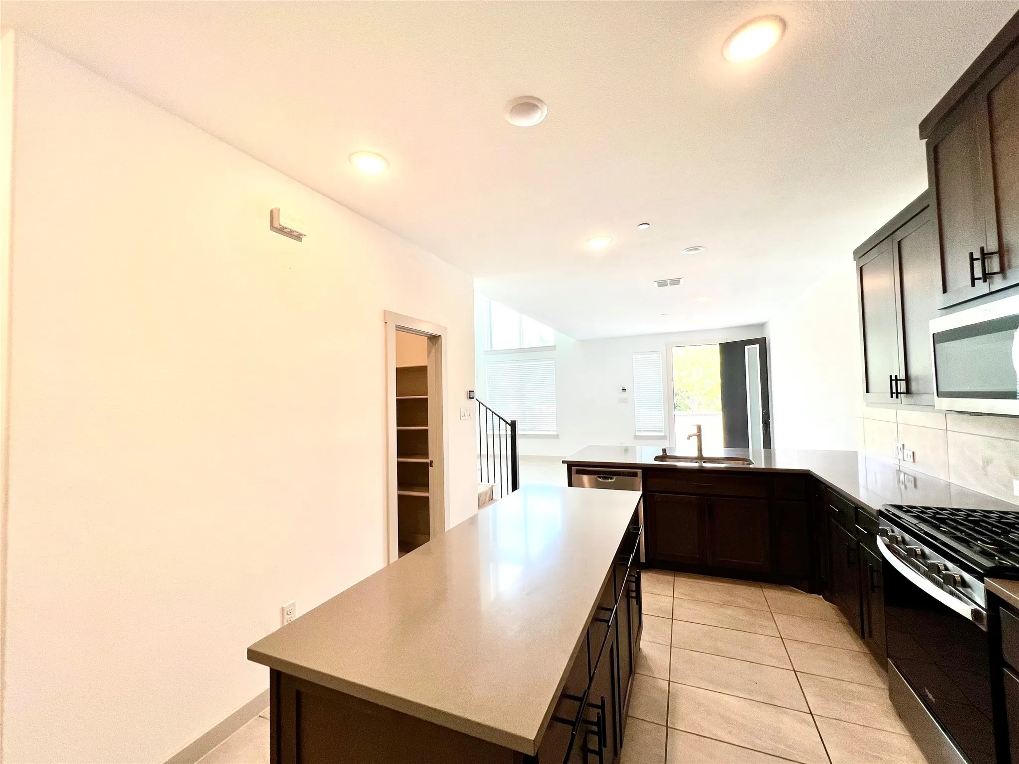 Kitchen featuring a kitchen island, light tile patterned floors, stainless steel appliances, sink, and kitchen peninsula