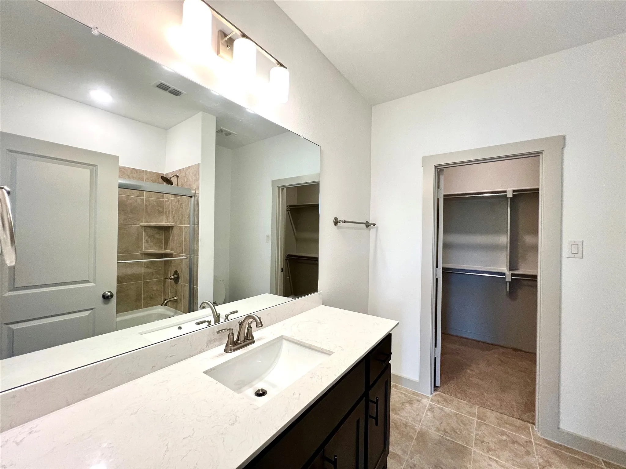 Bathroom featuring tile patterned flooring, vanity, and combined bath / shower with glass door