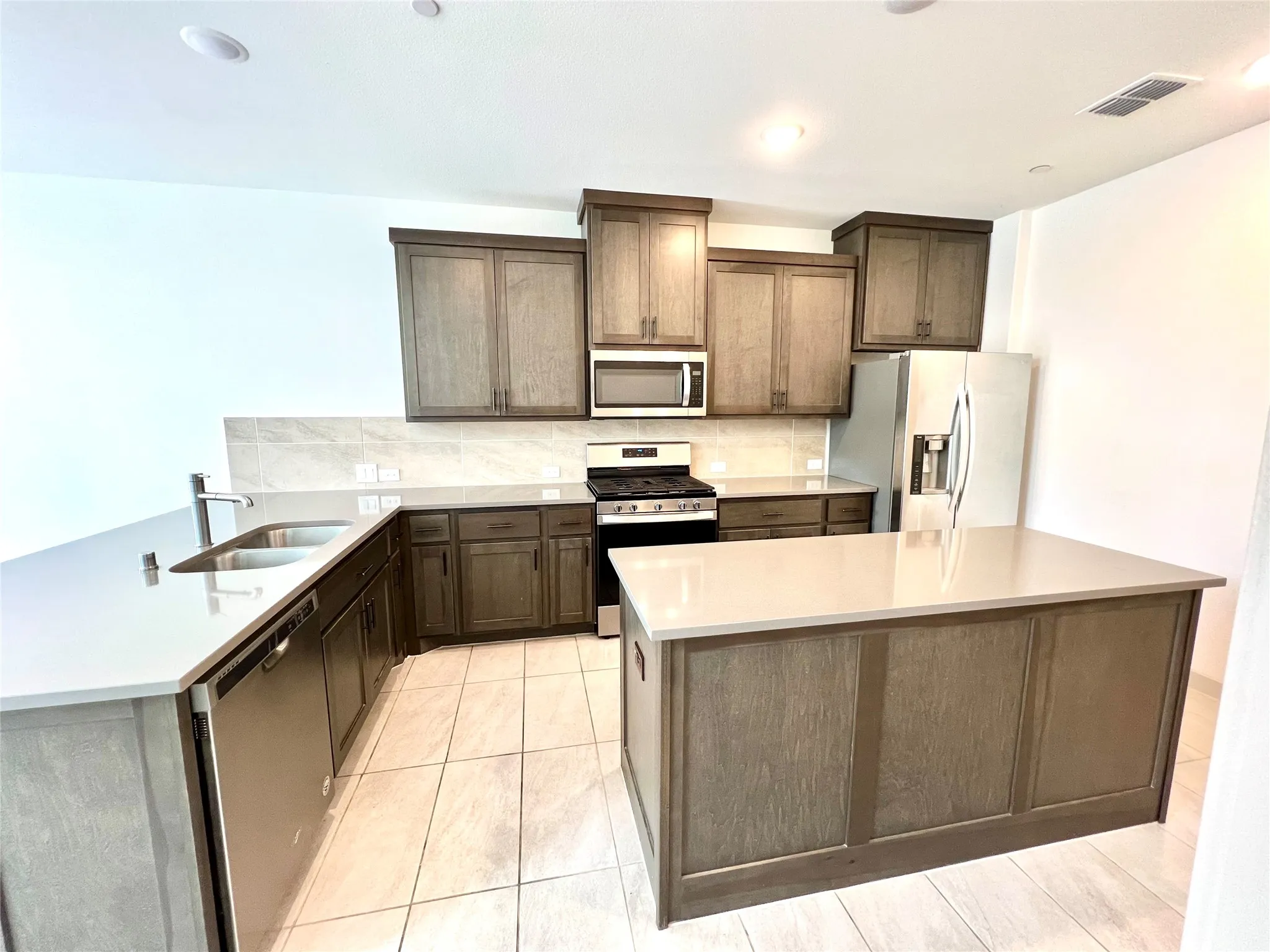 Kitchen featuring a center island, appliances with stainless steel finishes, tasteful backsplash, and sink