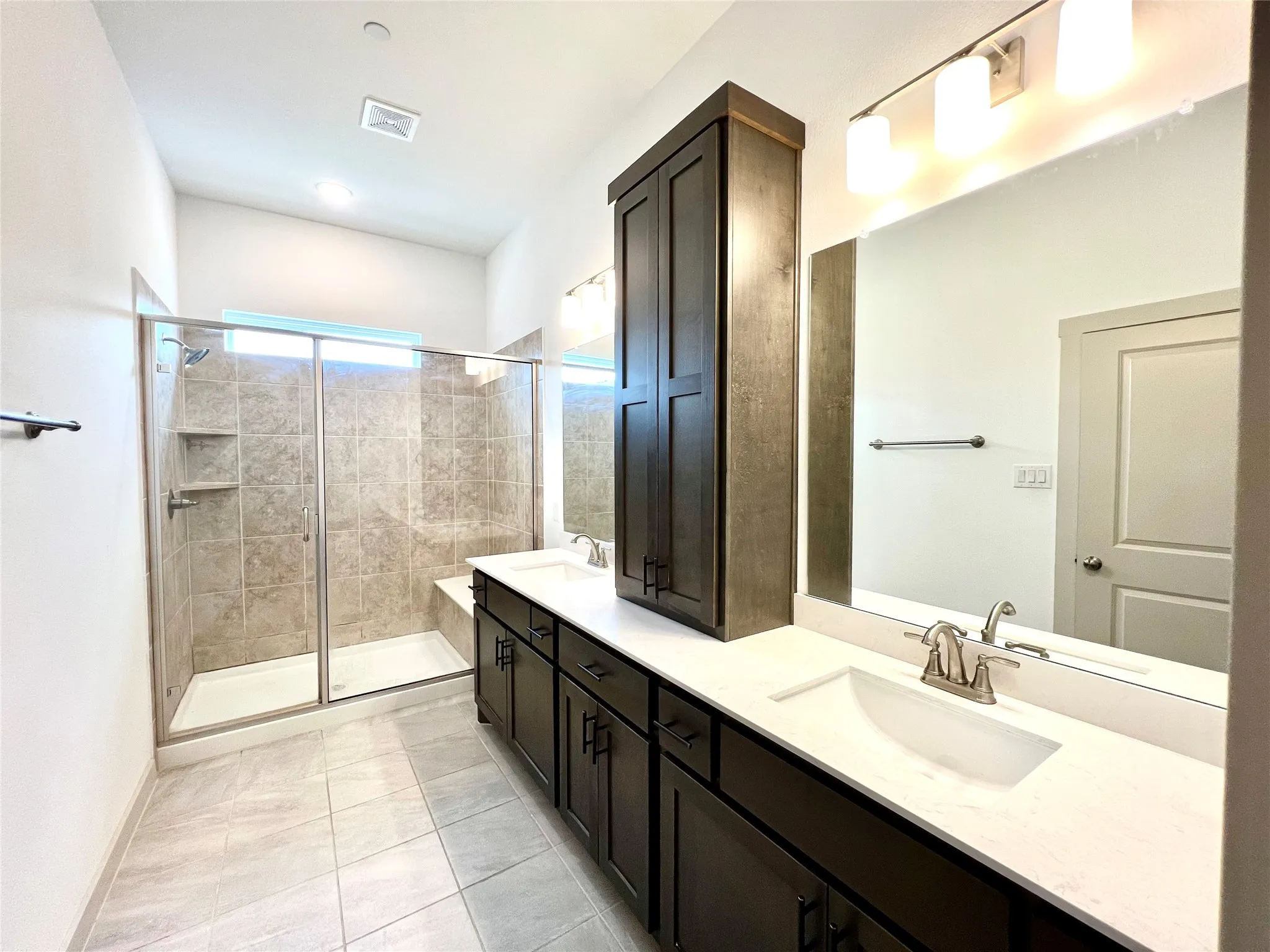 Bathroom featuring tile patterned flooring, an enclosed shower, and vanity
