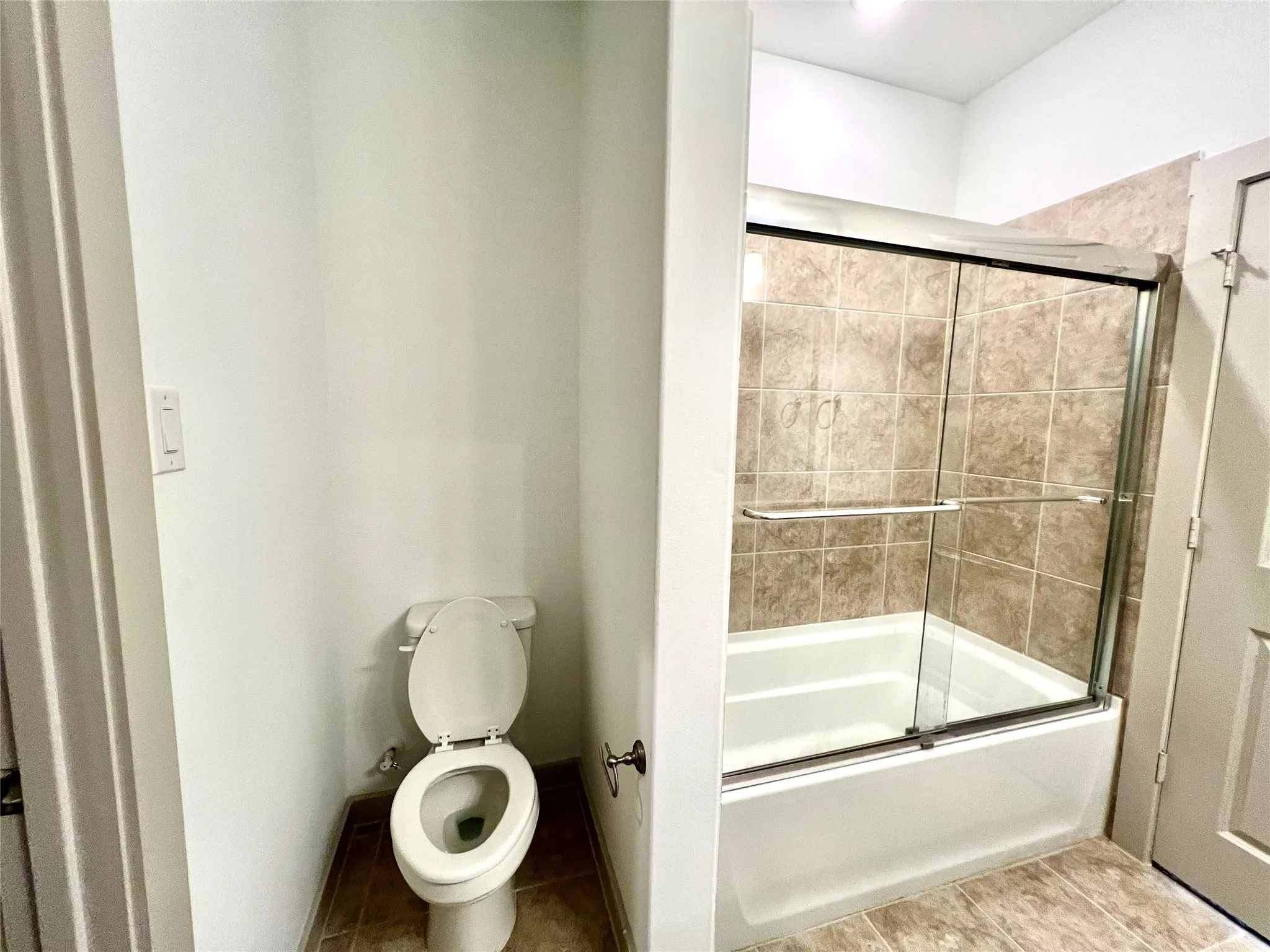 Bathroom with toilet and bath / shower combo with glass door