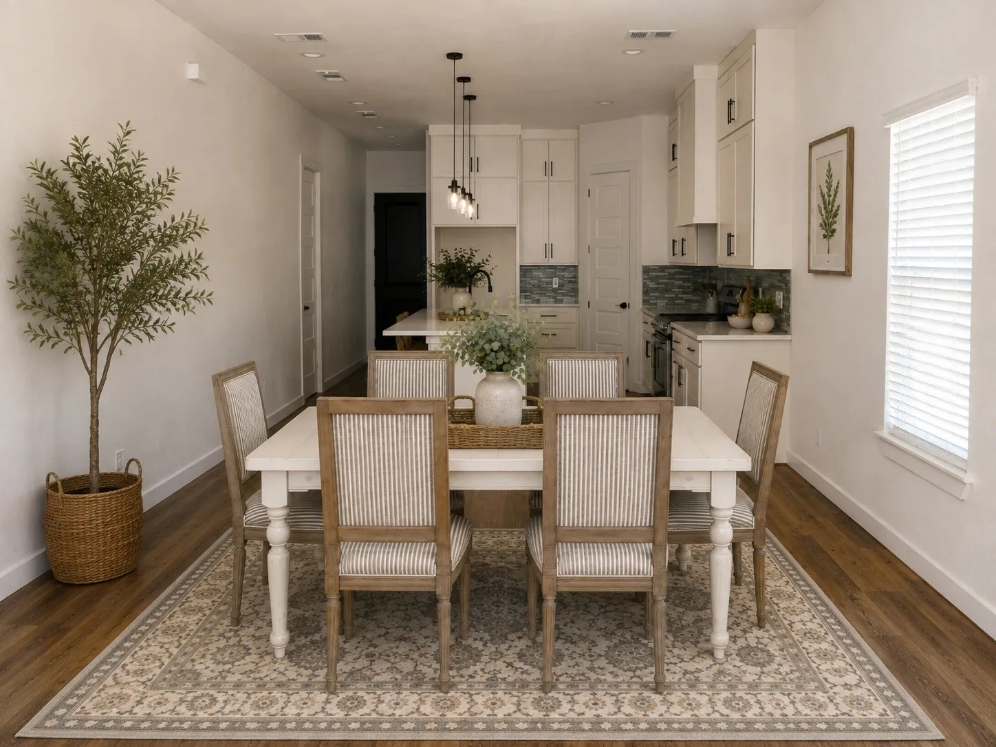 Open-concept living area featuring wood-finish flooring, recessed lighting, and a kitchen with white cabinetry and a tile backsplash