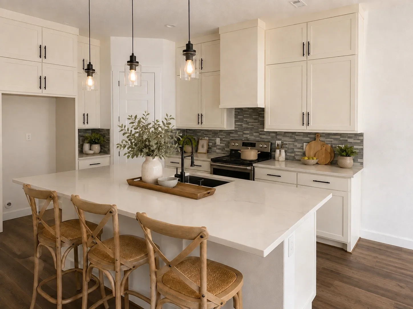 Kitchen featuring a large central island with a light-toned countertop, white cabinetry with dark hardware, a tile backsplash, wood-finish flooring, and pendant lighting