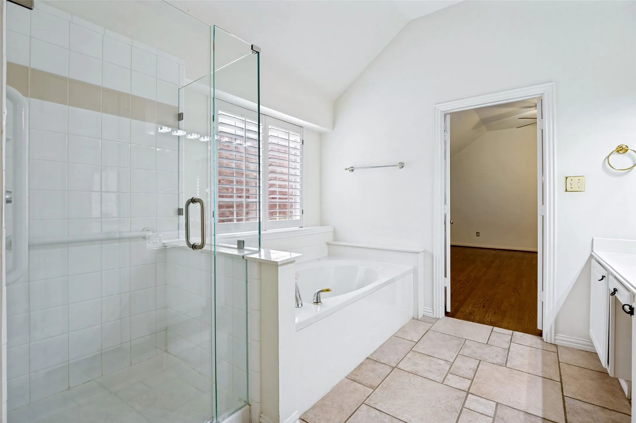 Bathroom featuring a glass-enclosed shower, a built-in tub with deck, white cabinetry, and a vanity with an integrated sink