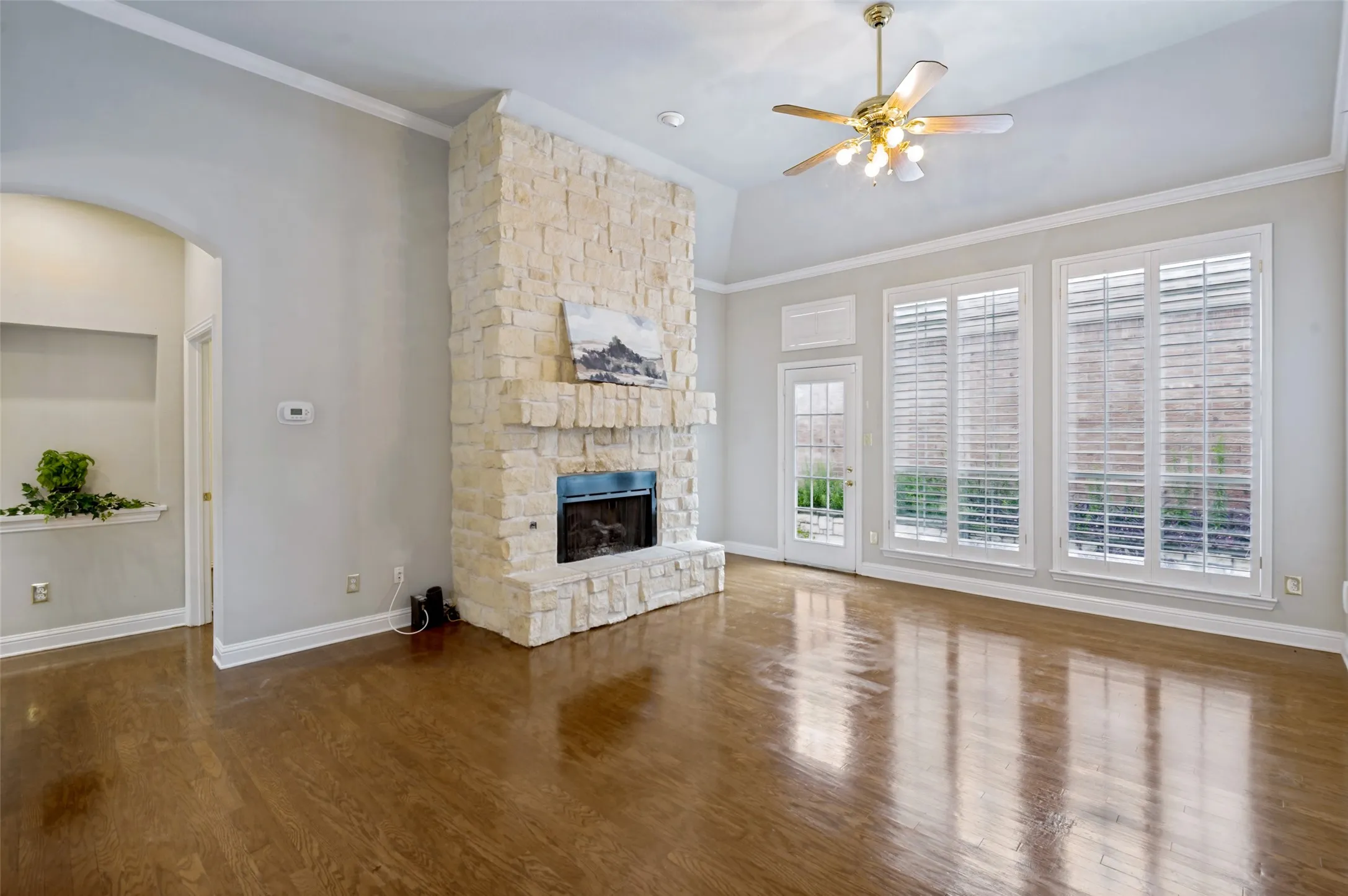 Spacious living area featuring a floor-to-ceiling stone fireplace, high vaulted ceilings, and rich wood-finish flooring