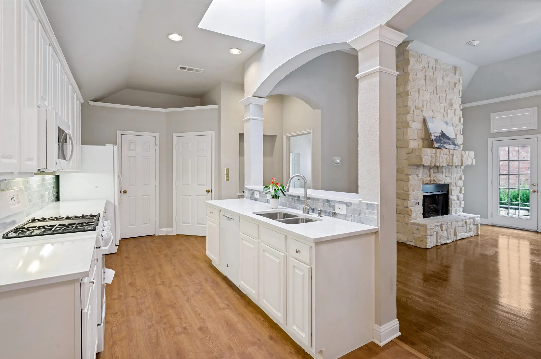 Open-concept kitchen featuring white cabinetry light blue backsplash, light-toned countertops, and a subway tile backsplash