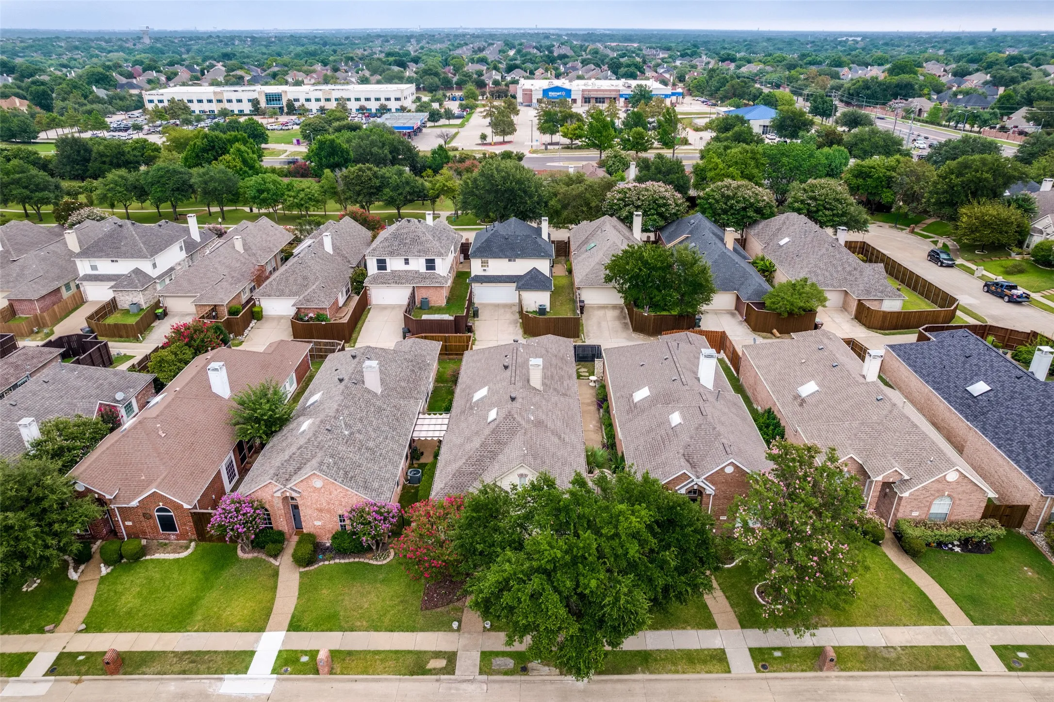 Aerial perspective of a residential street with an array of traditional brick and siding homes, each featuring gabled roofs and private driveways
