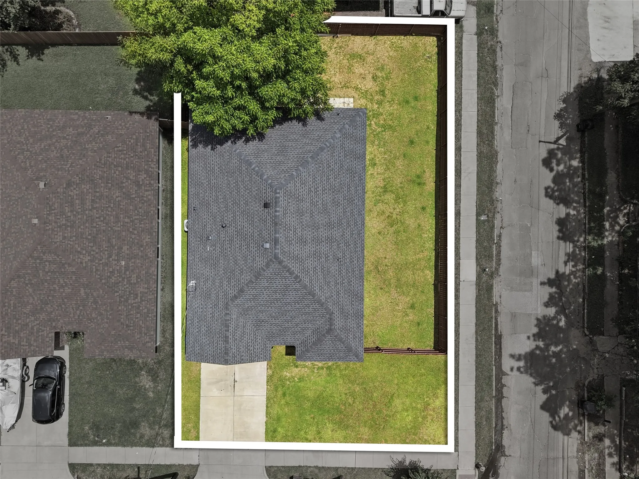 Aerial view showcasing the property's perimeter, a gray shingle roof, a concrete driveway, and a spacious green lawn