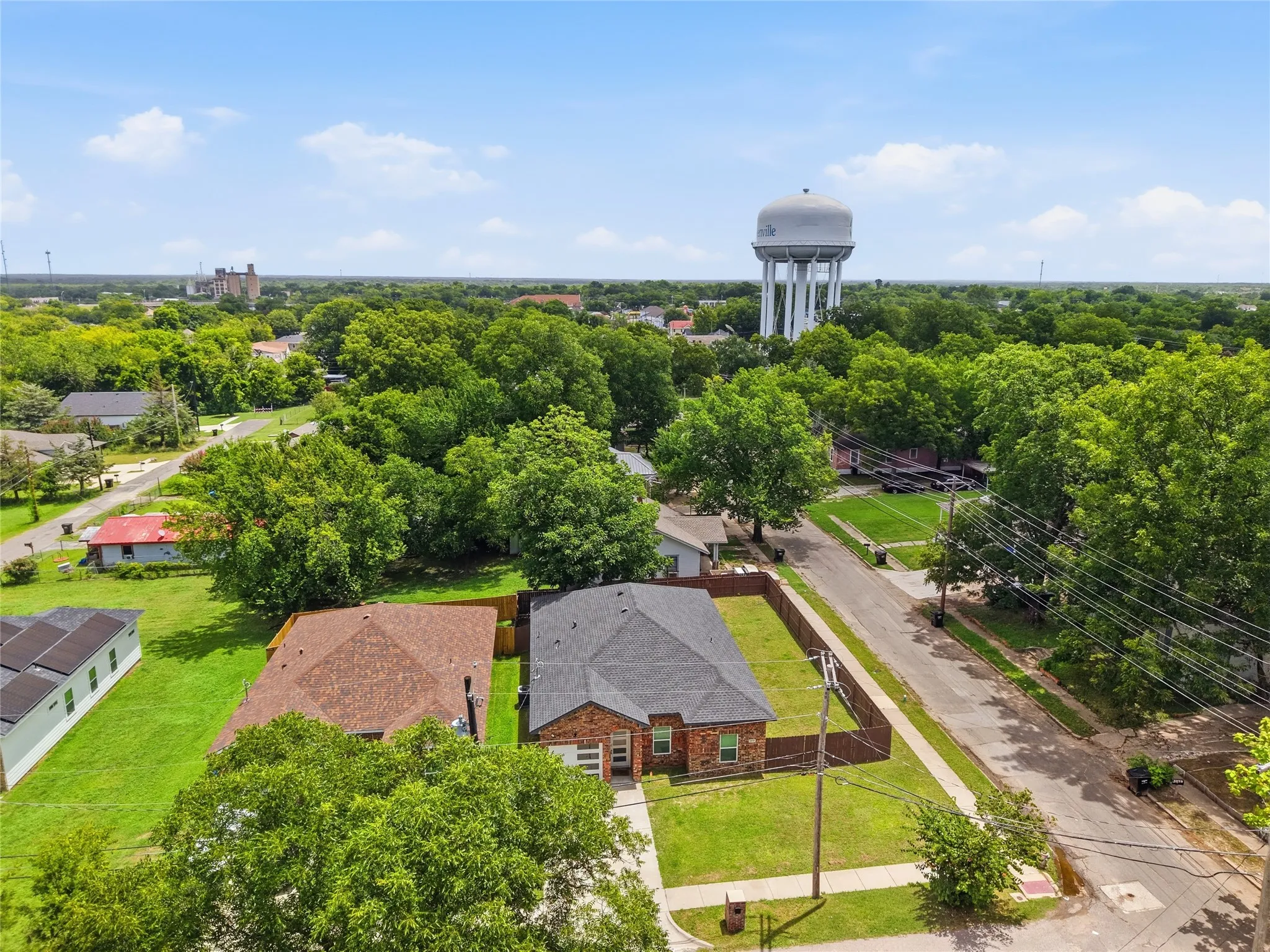 Aerial perspective showcasing a single-story brick residence with a dark shingle roof