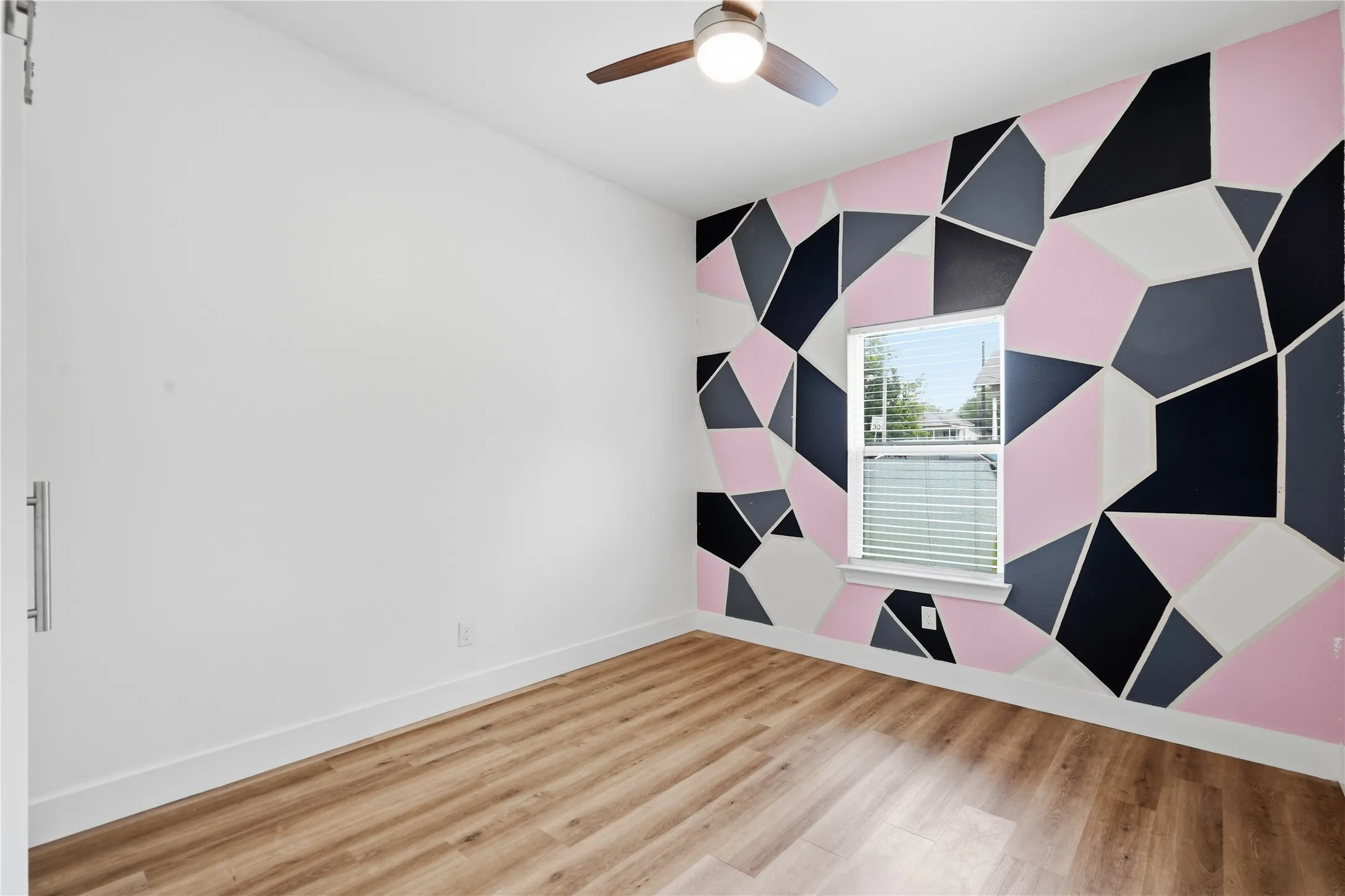 Room featuring a geometric accent wall in pink, black, gray, and white