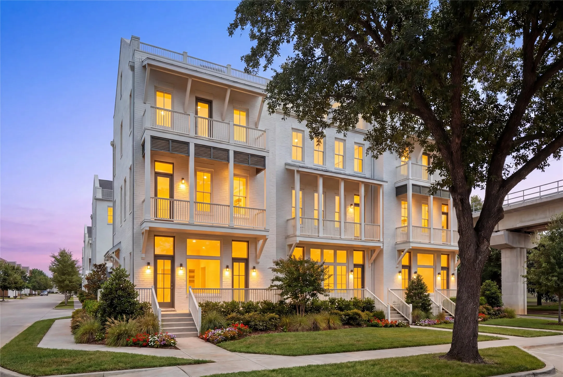 Contemporary townhome facade featuring white brick, multiple balconies with metal railings, and prominent windows
