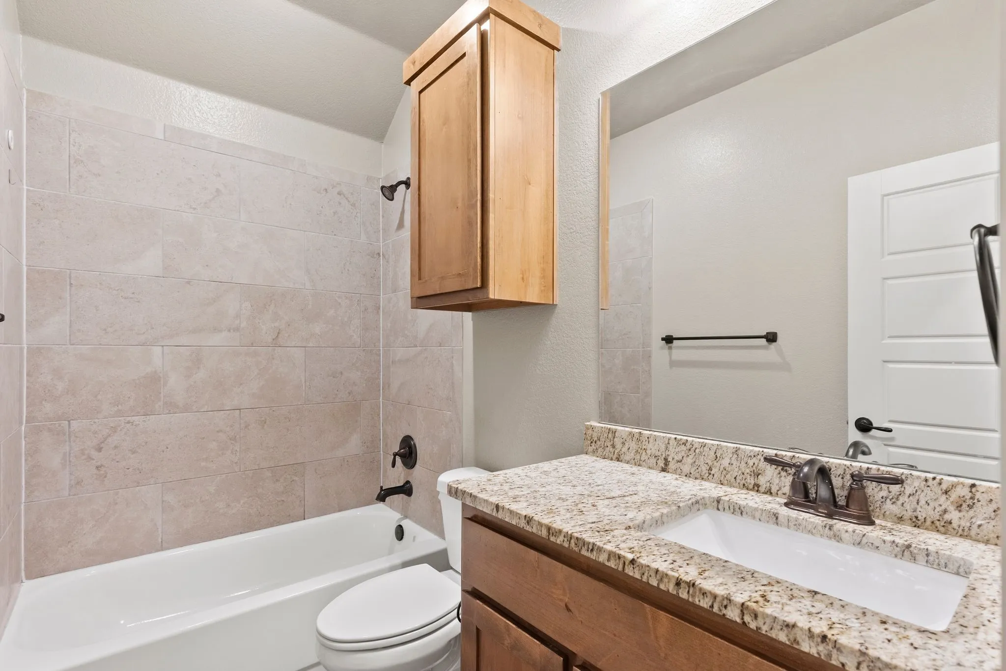 Guest bathroom featuring shower / bathtub combination, vanity with granite countertop