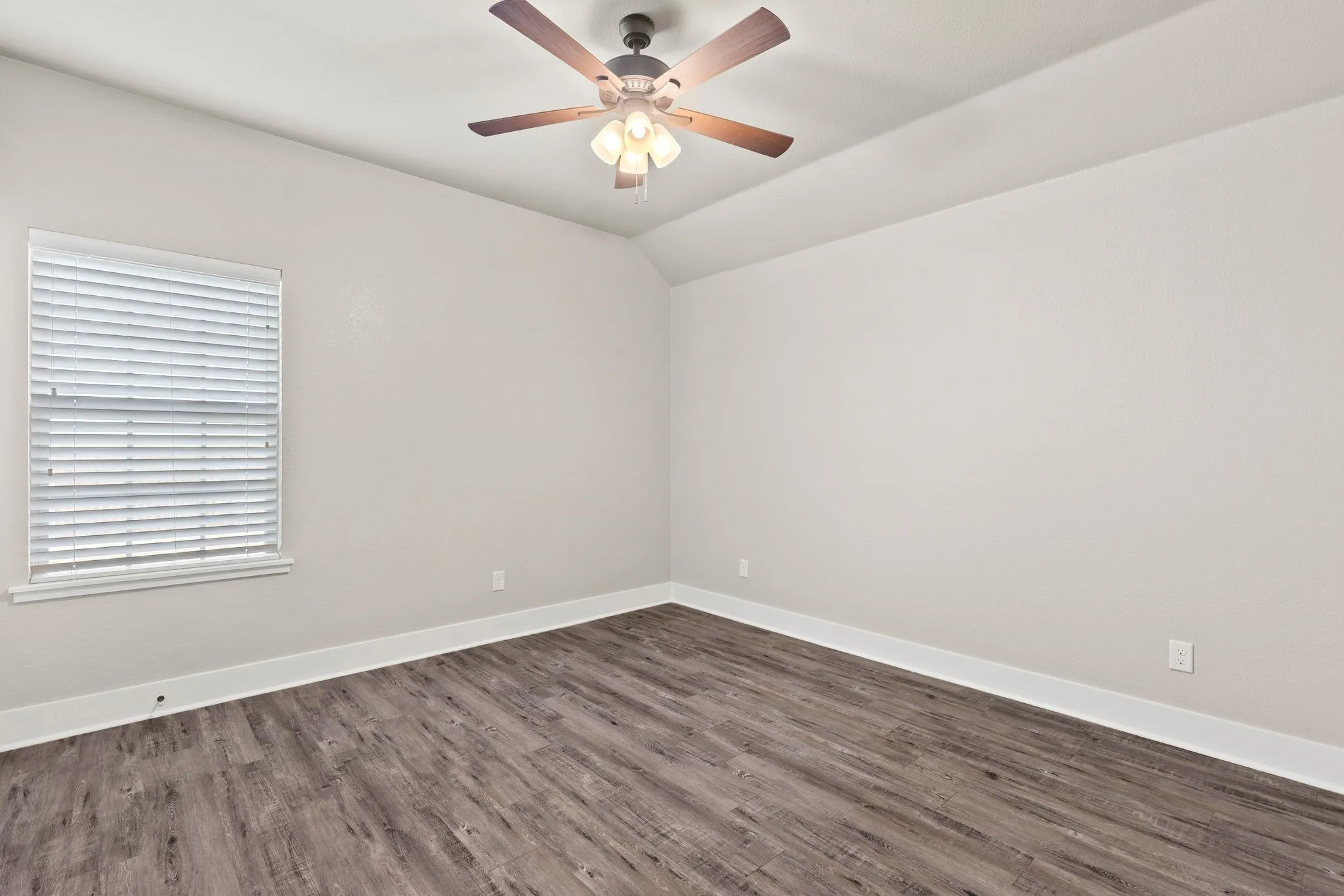 Third bedroom with vaulted ceiling, dark wood-style floors, and ceiling fan