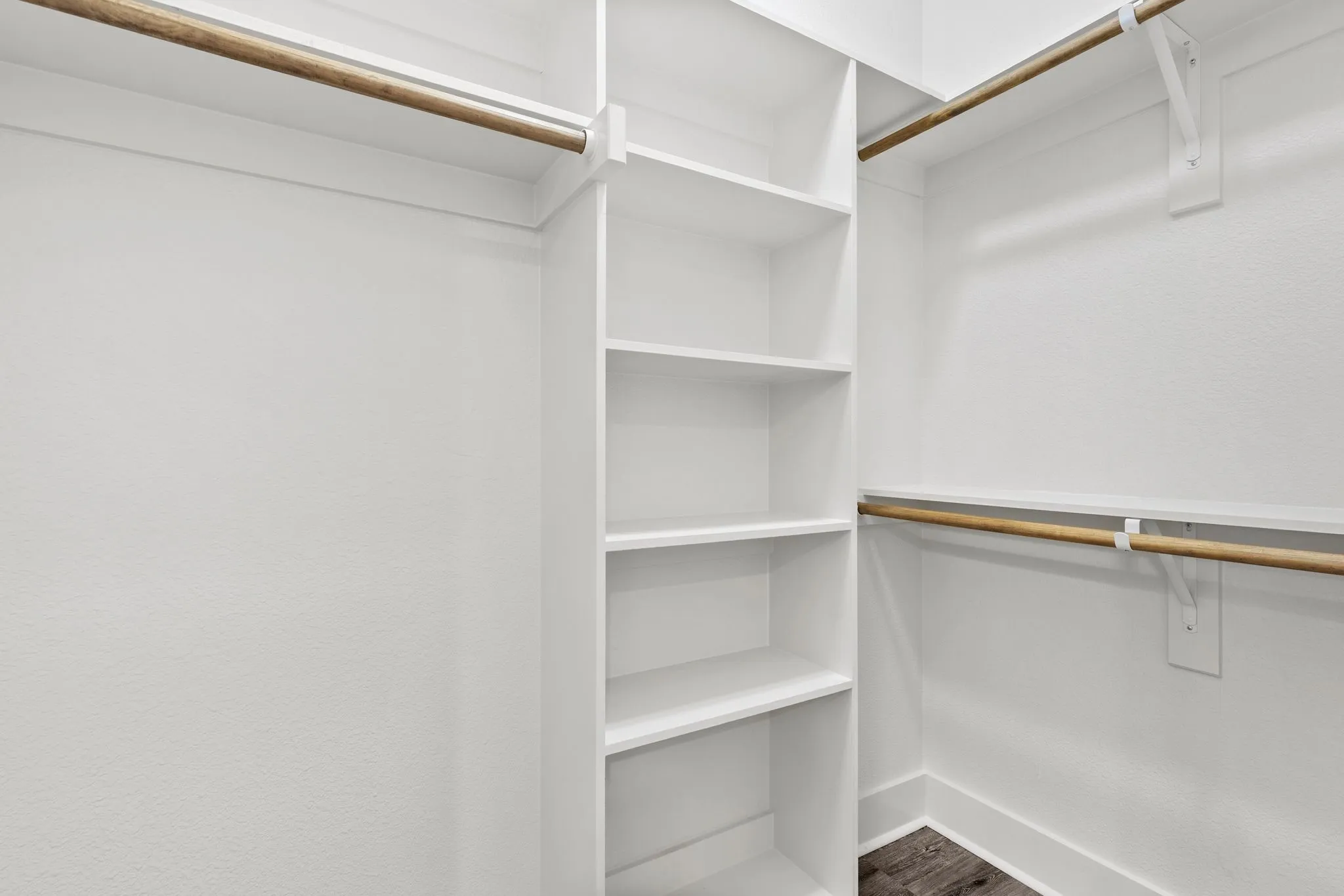 Walk in closet with dark wood-style flooring