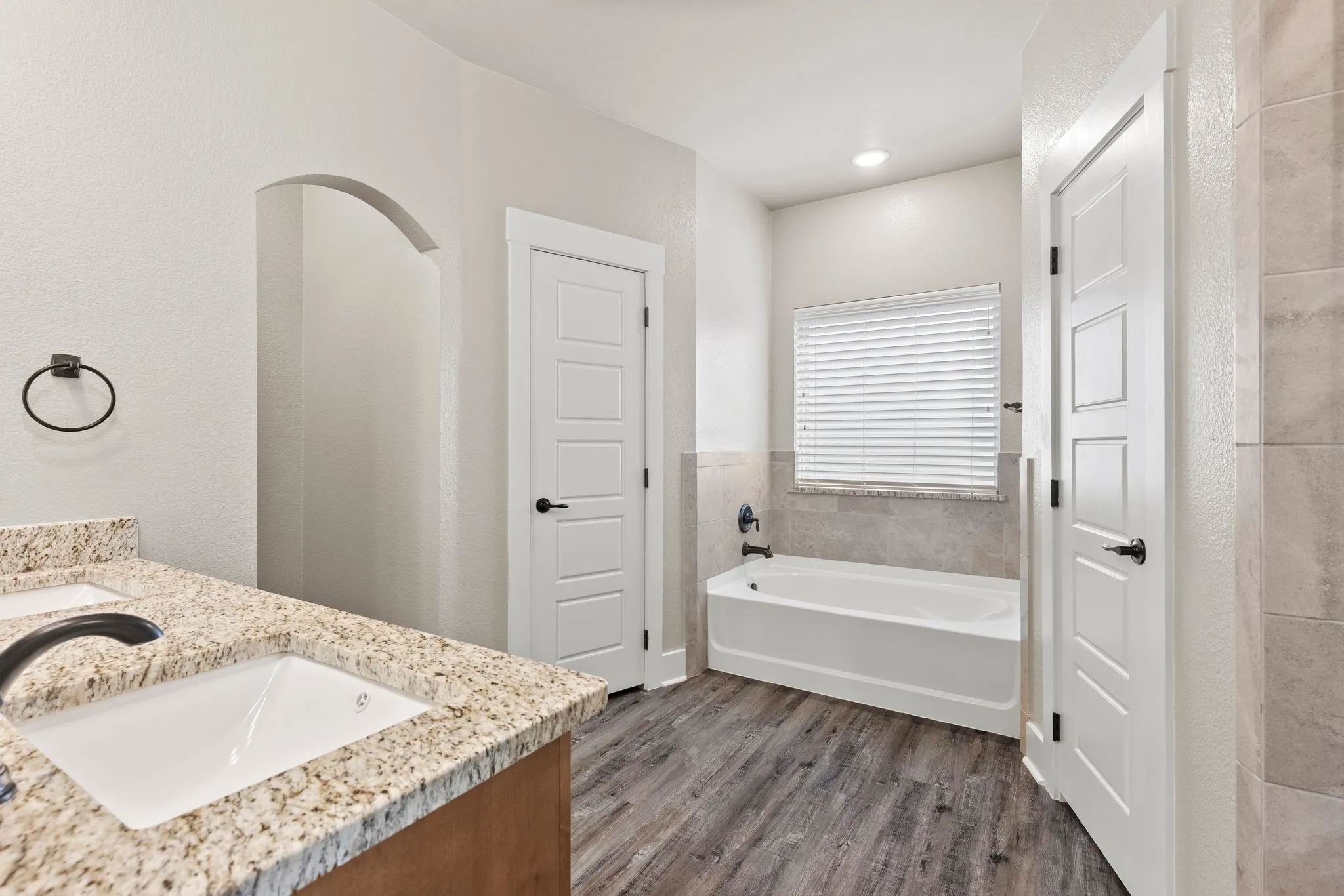 Bathroom with double vanity, dark wood-type flooring, and a garden tub