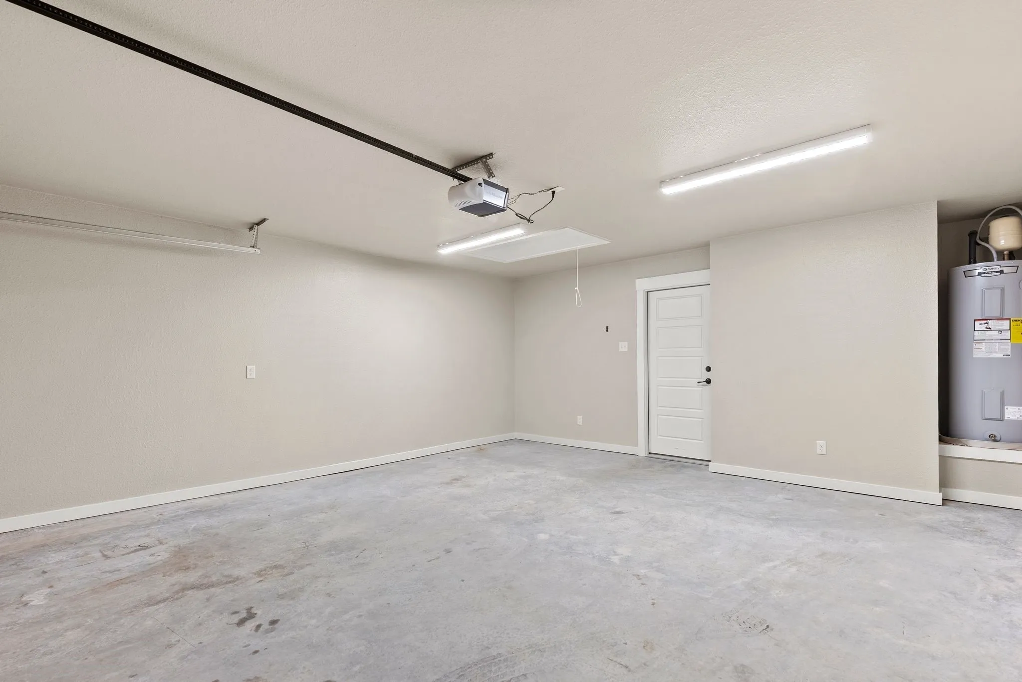 Finished-out garage featuring electric water heater and baseboards